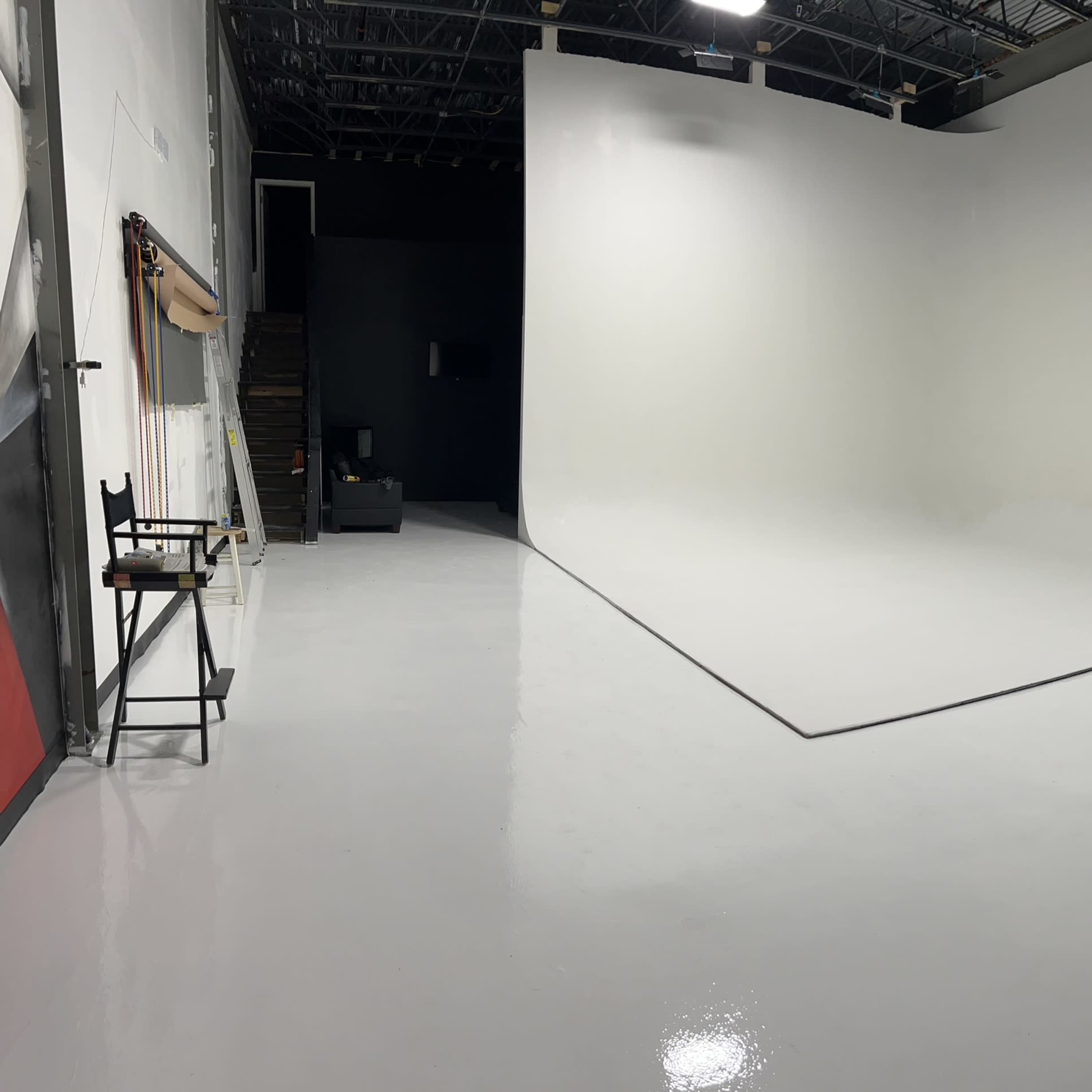 A spacious photography studio with a seamless white backdrop and polished flooring.