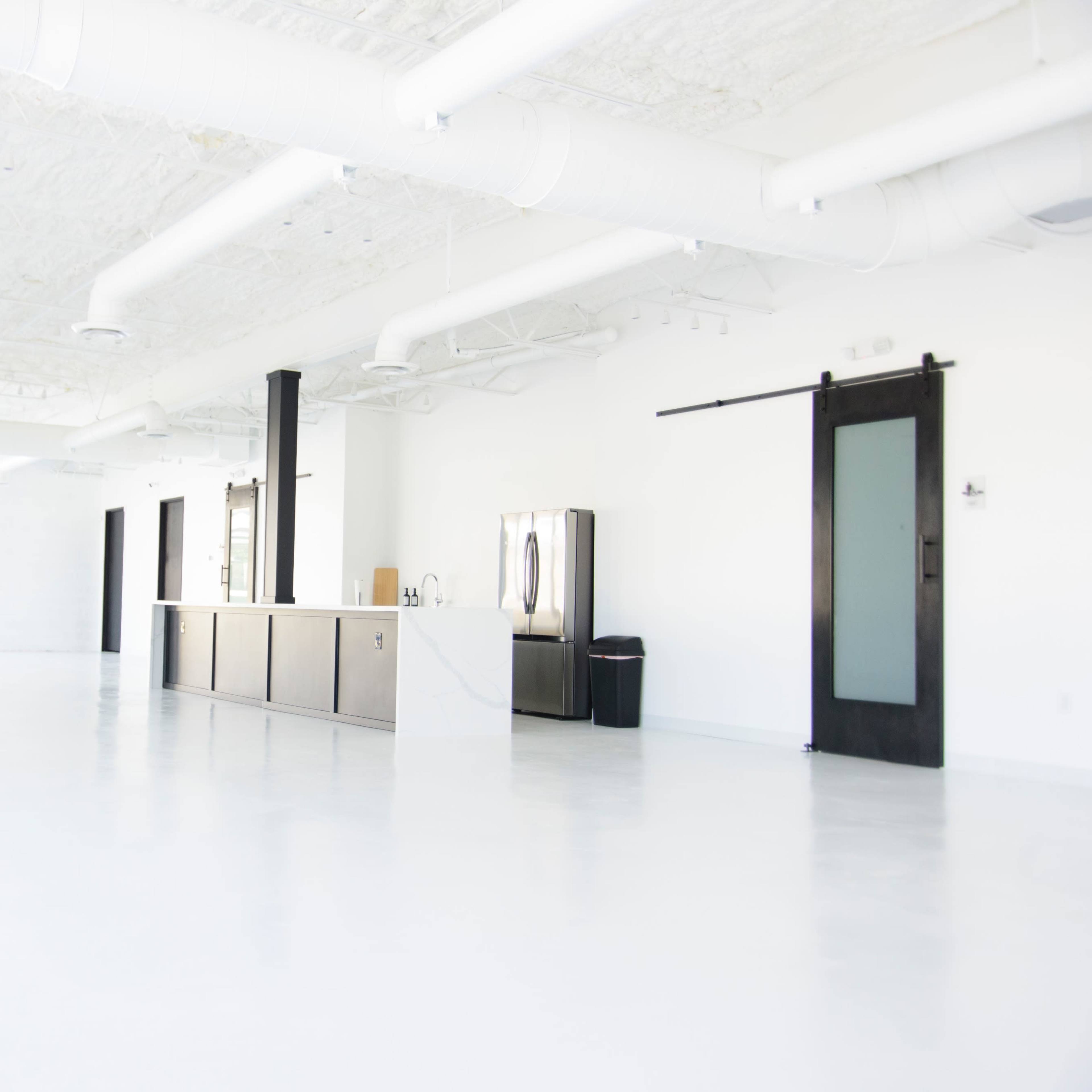 A spacious, well-lit interior with a sleek counter and minimal furniture against a white backdrop.