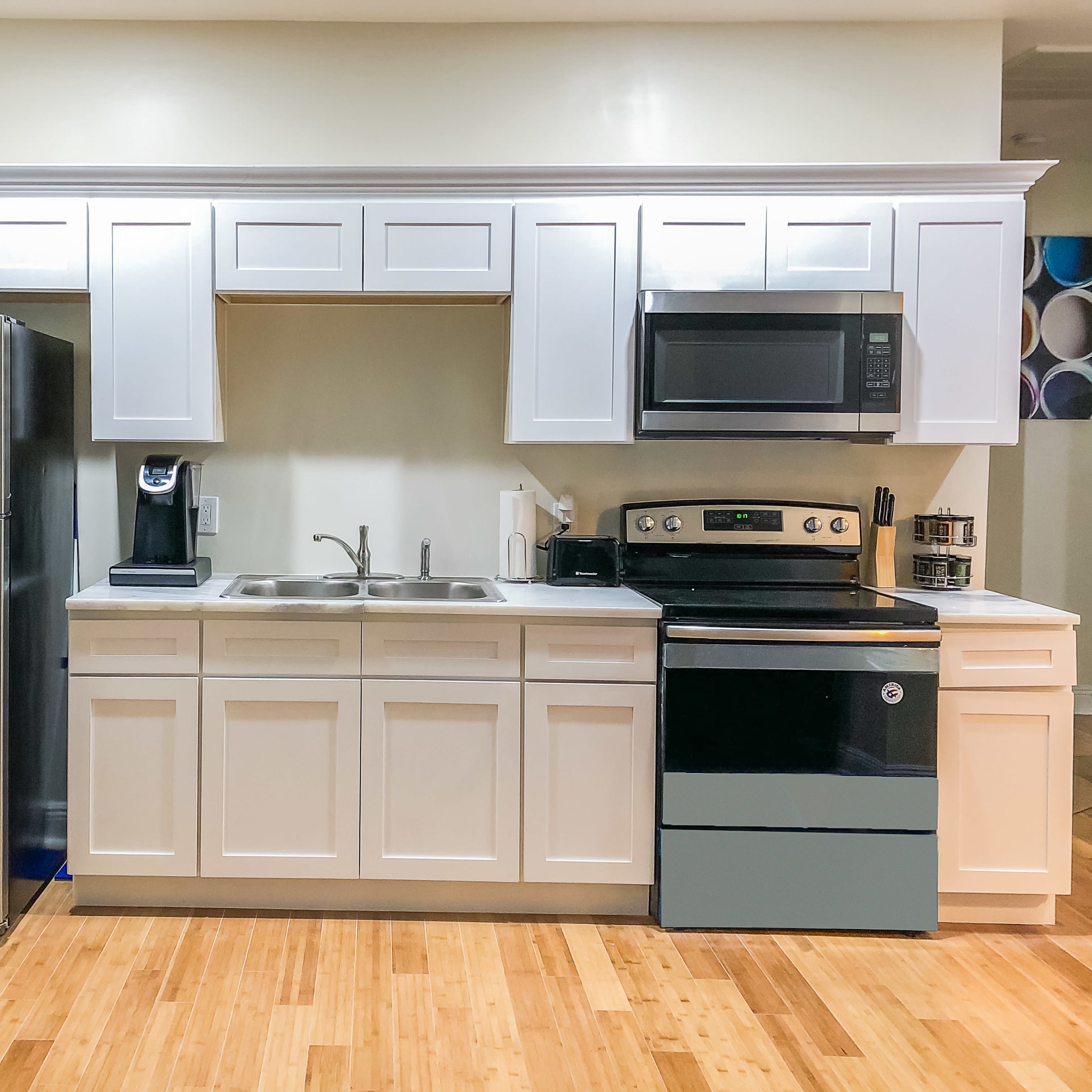 A modern kitchen featuring stainless steel appliances, white cabinetry, and a bamboo floor.