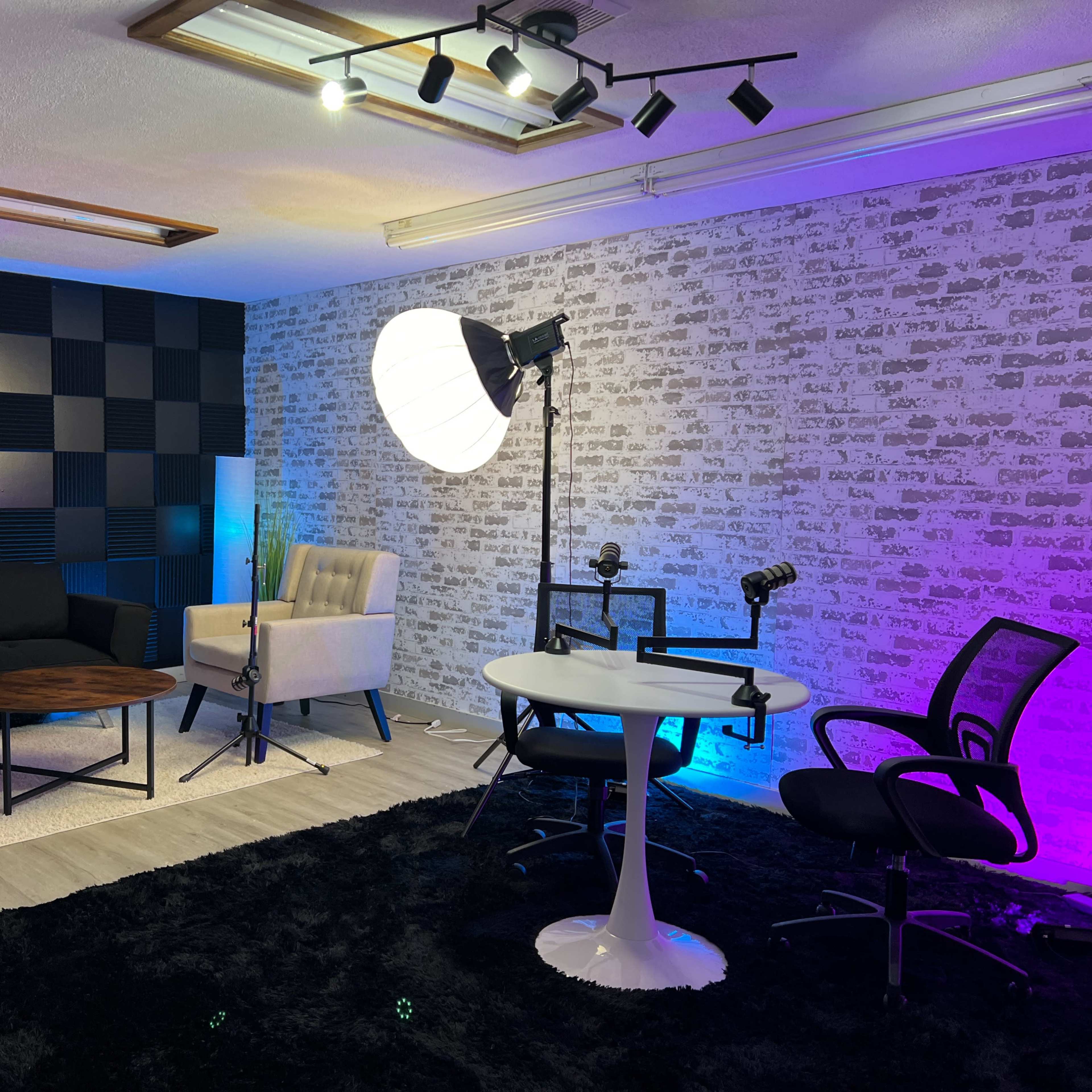 A modern recording studio setup featuring a black and white textured wall, a couch, and various studio equipment, including microphones and soft lighting.