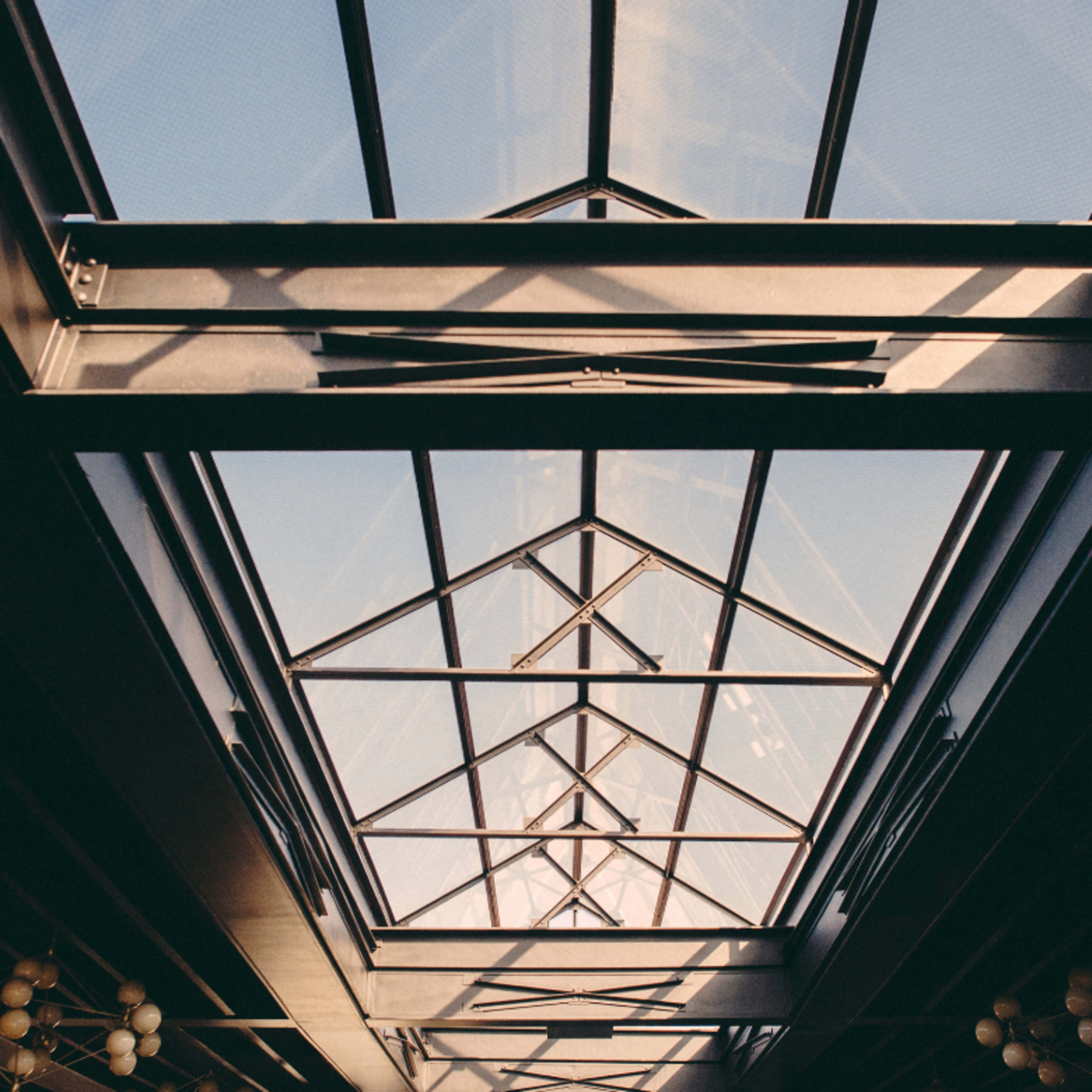 A skylight with a geometric design, framed by a dark interior, allowing sunlight to illuminate the space below.