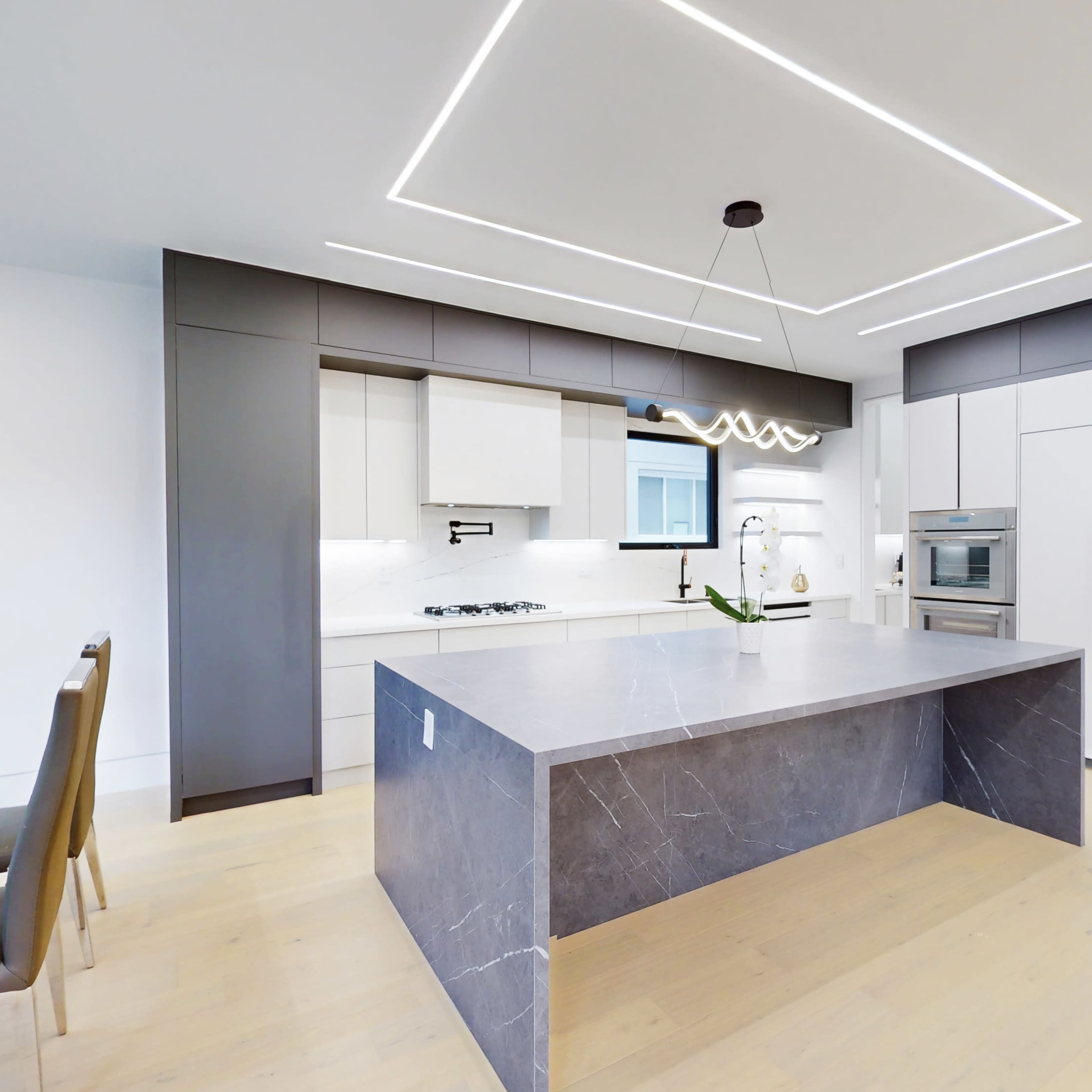 The kitchen features a central island with a dark marble countertop, modern cabinetry, and integrated appliances.