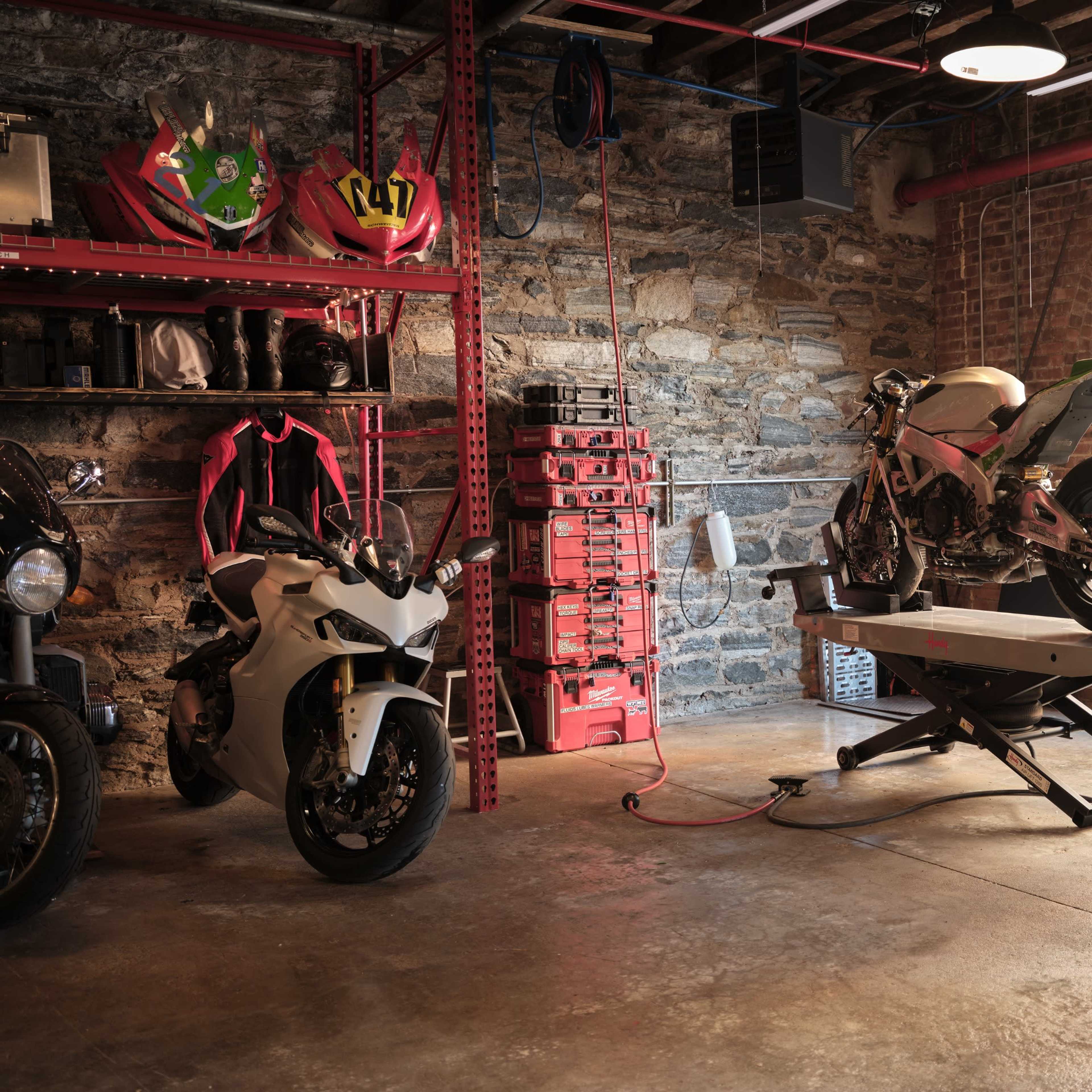 A garage featuring several motorcycles, a workbench, and an American flag displayed on the wall.