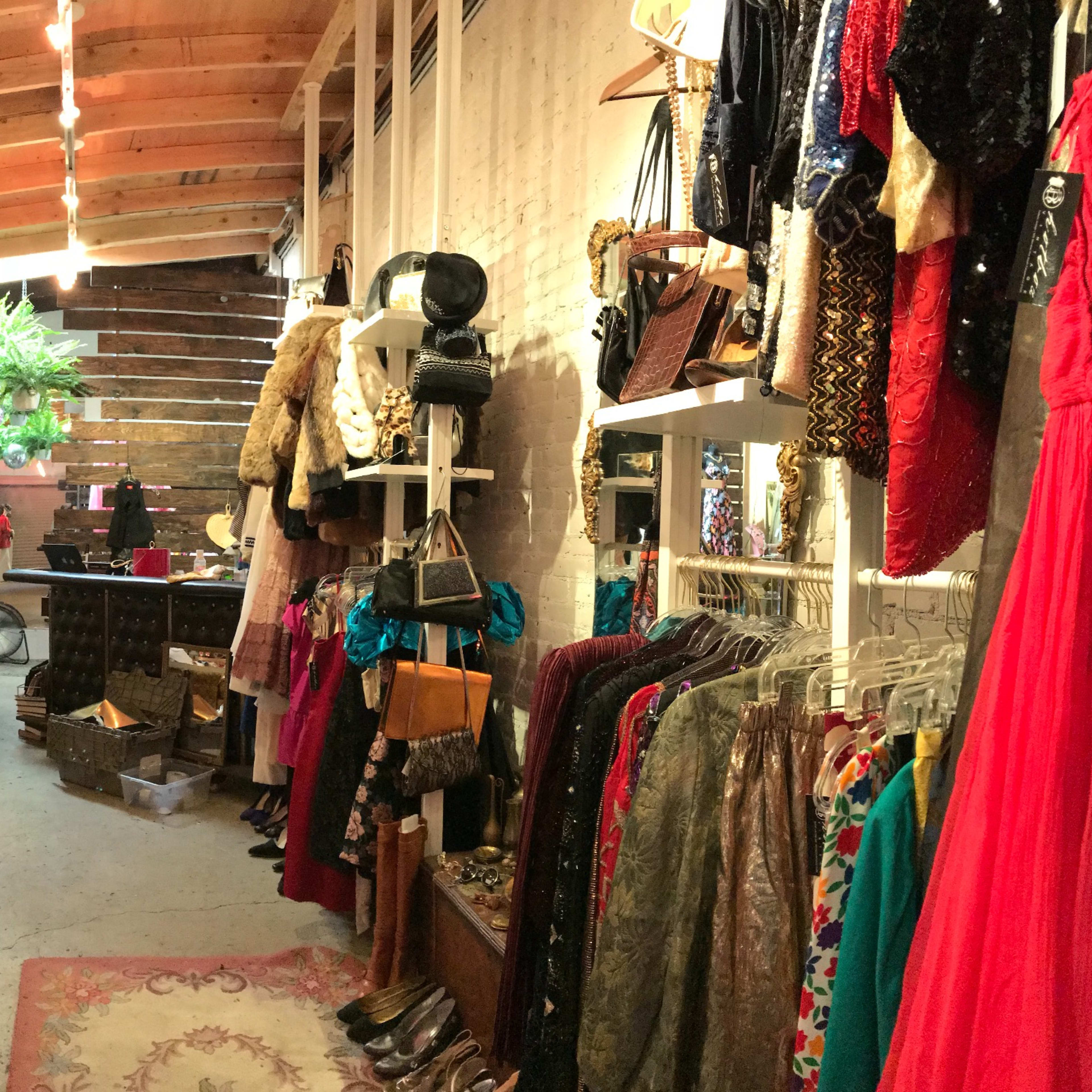A boutique interior with clothing racks, a seating area, and various accessories displayed on shelves.