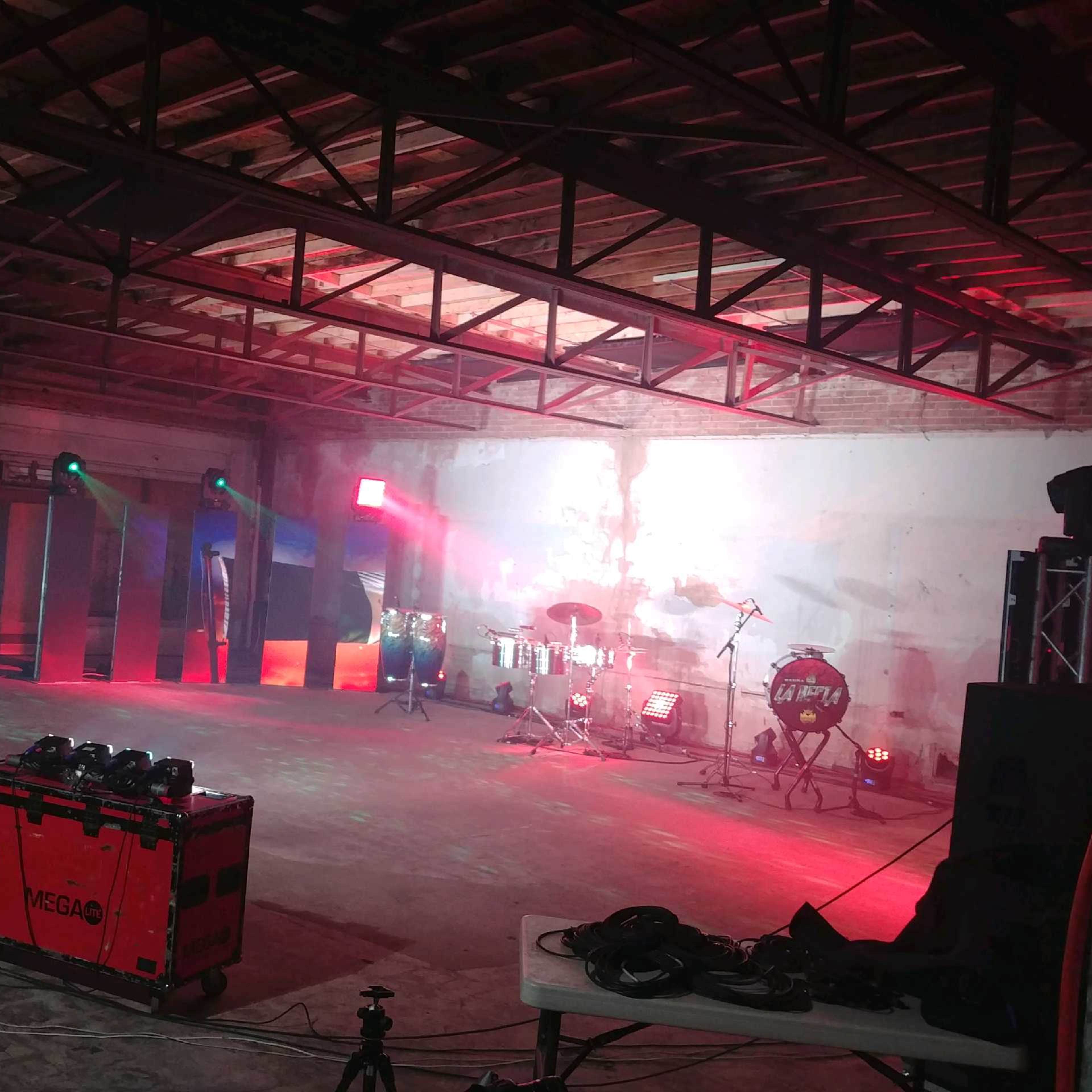 An empty industrial space set up for a live music performance, with stage equipment and lighting arranged throughout.
