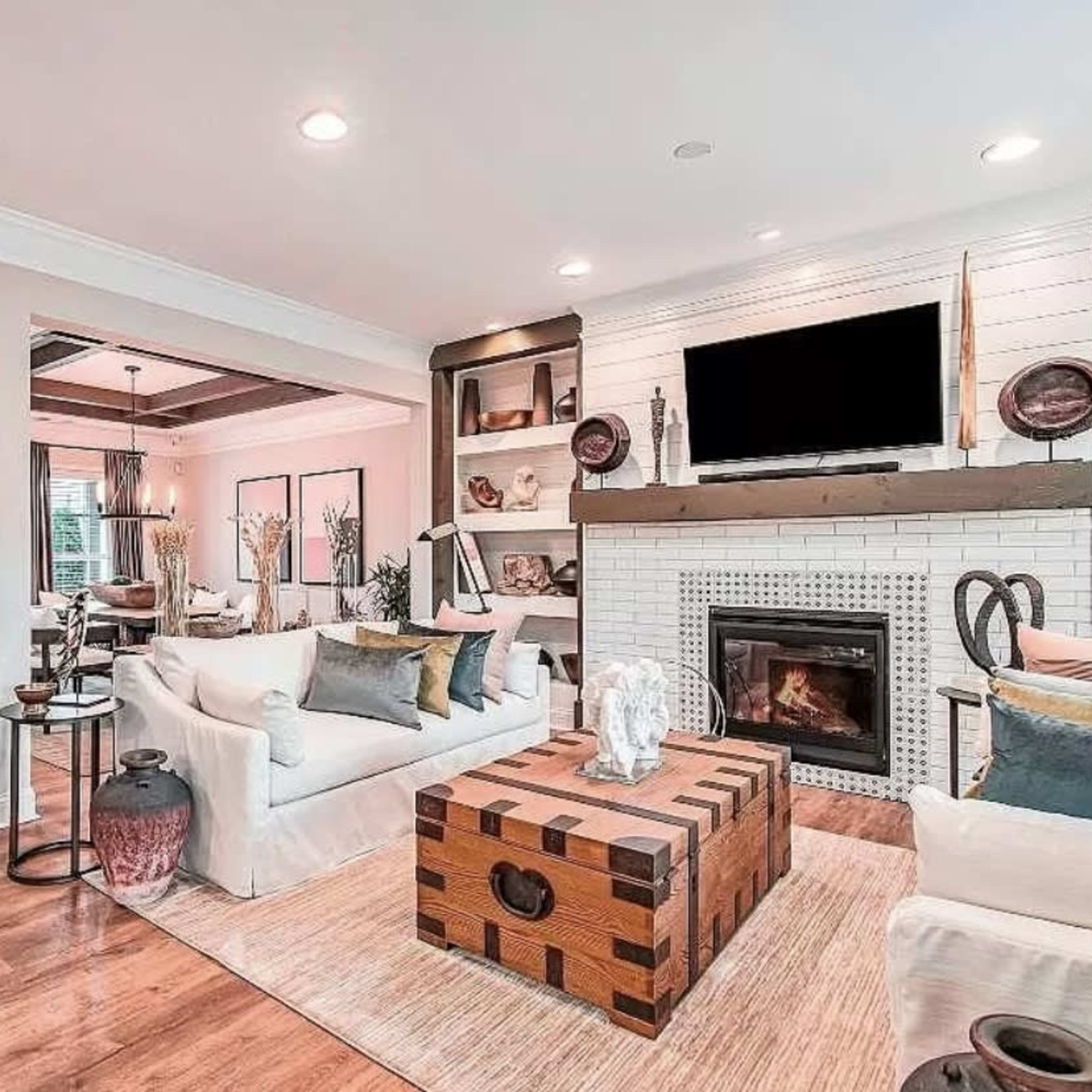 The living room features a white couch, a wooden coffee table, built-in shelves, and a fireplace, with a television mounted above it.