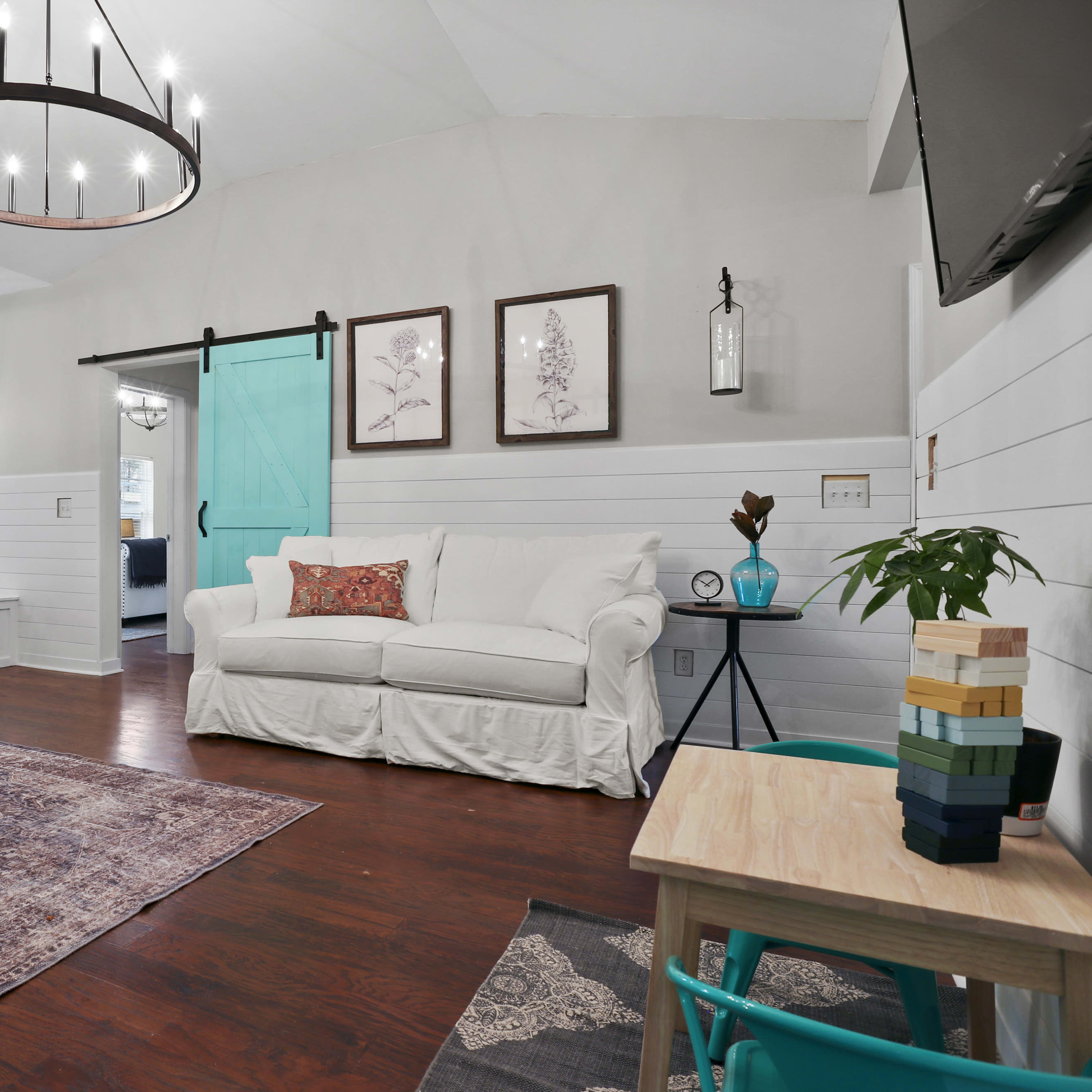 The living room features a white sofa, a wooden coffee table, and a sliding barn door leading to the kitchen.