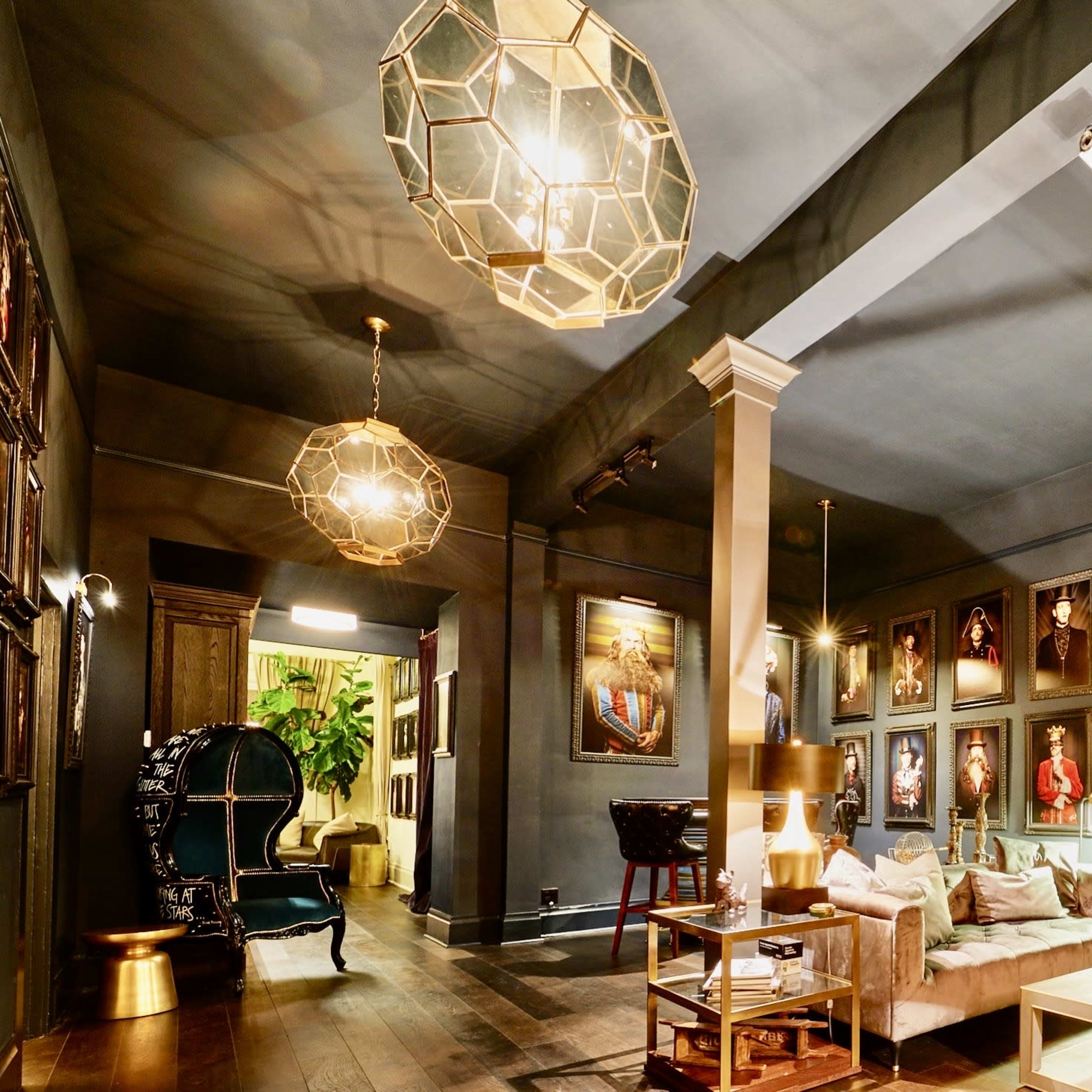 A stylish interior with framed portraits on the walls, modern lighting fixtures, and a mix of seating arrangements.