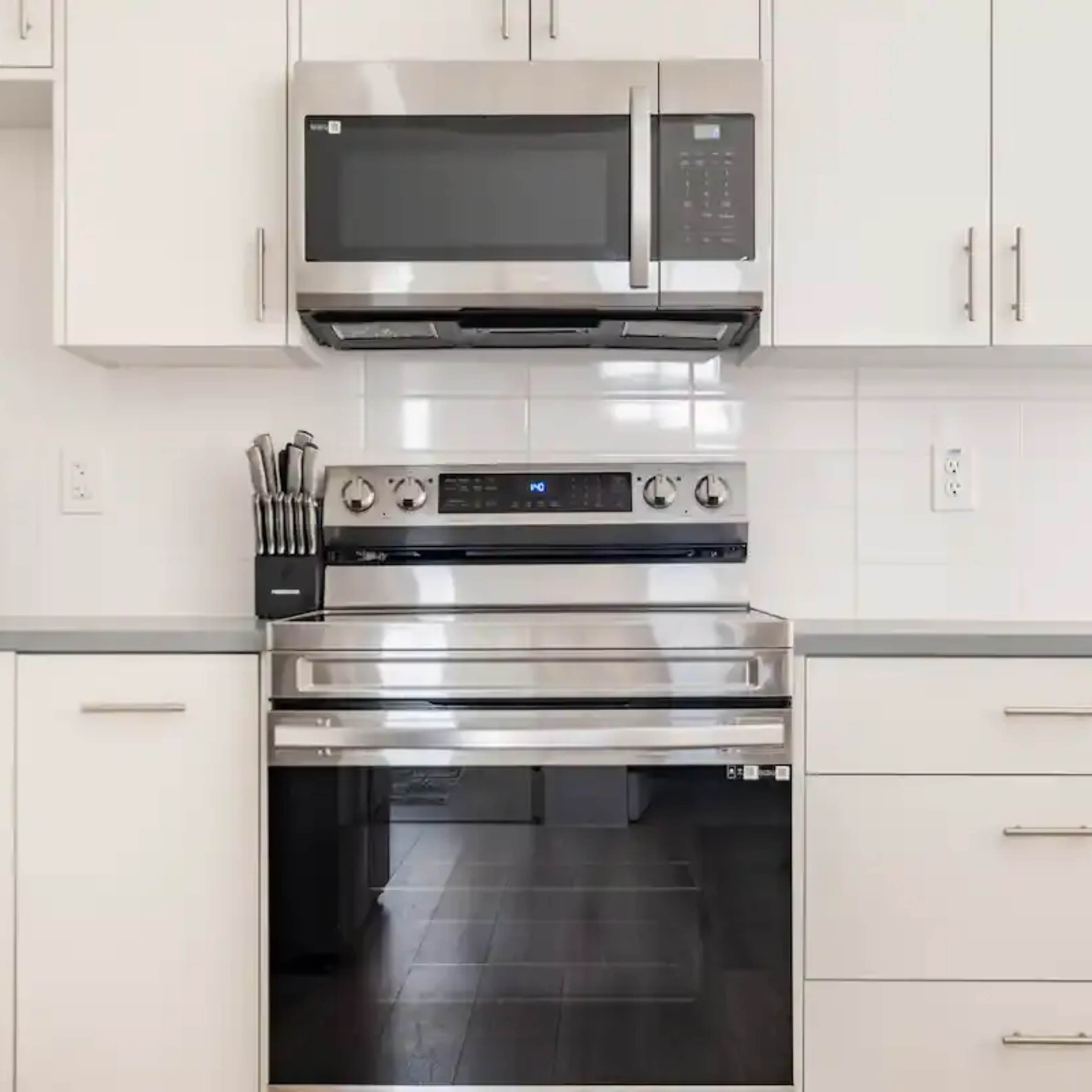 A modern kitchen with a stainless steel oven and microwave installed above it, along with white cabinetry and a countertop.