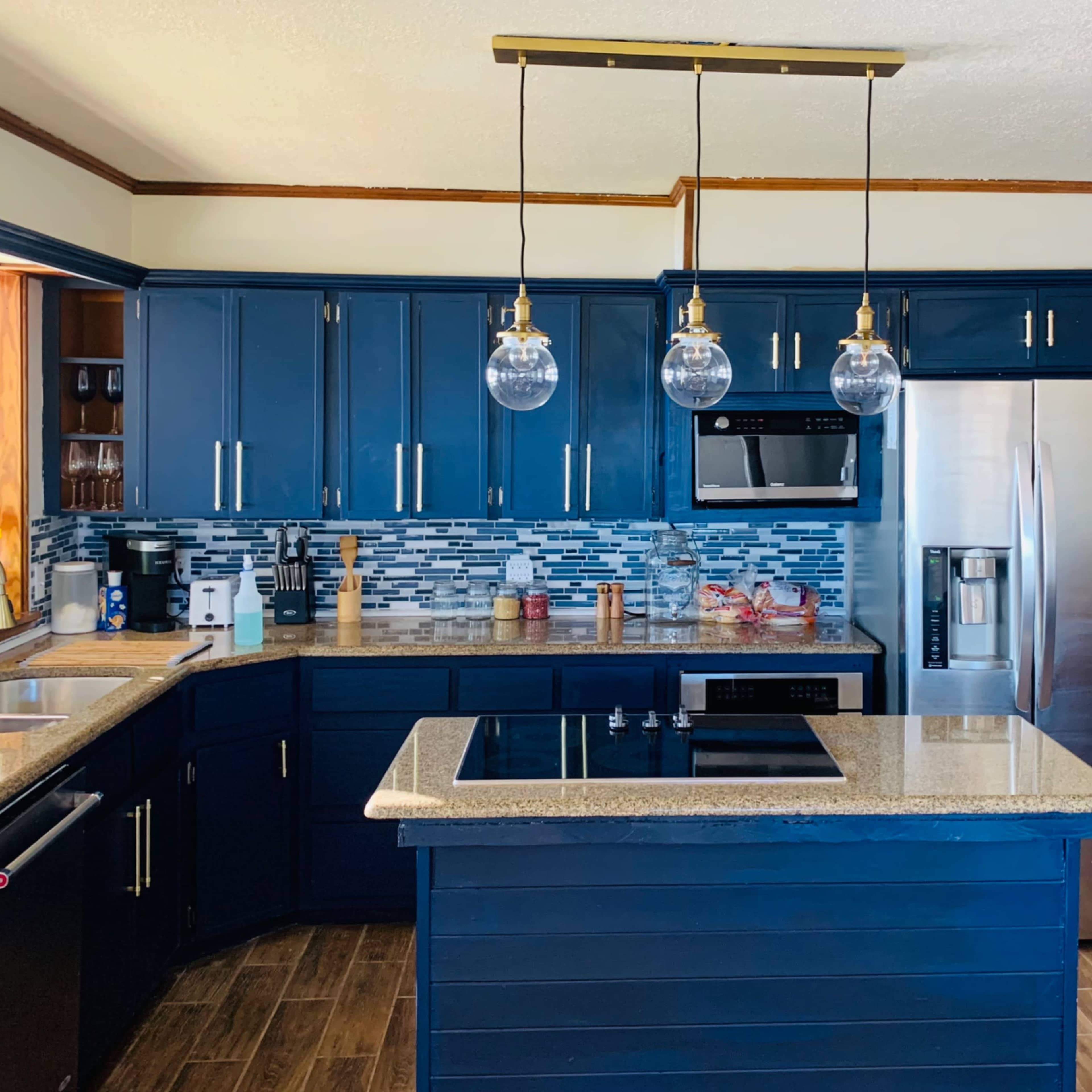 The kitchen features navy blue cabinets, a granite countertop, and modern appliances, including a stainless steel refrigerator and an electric cooktop.