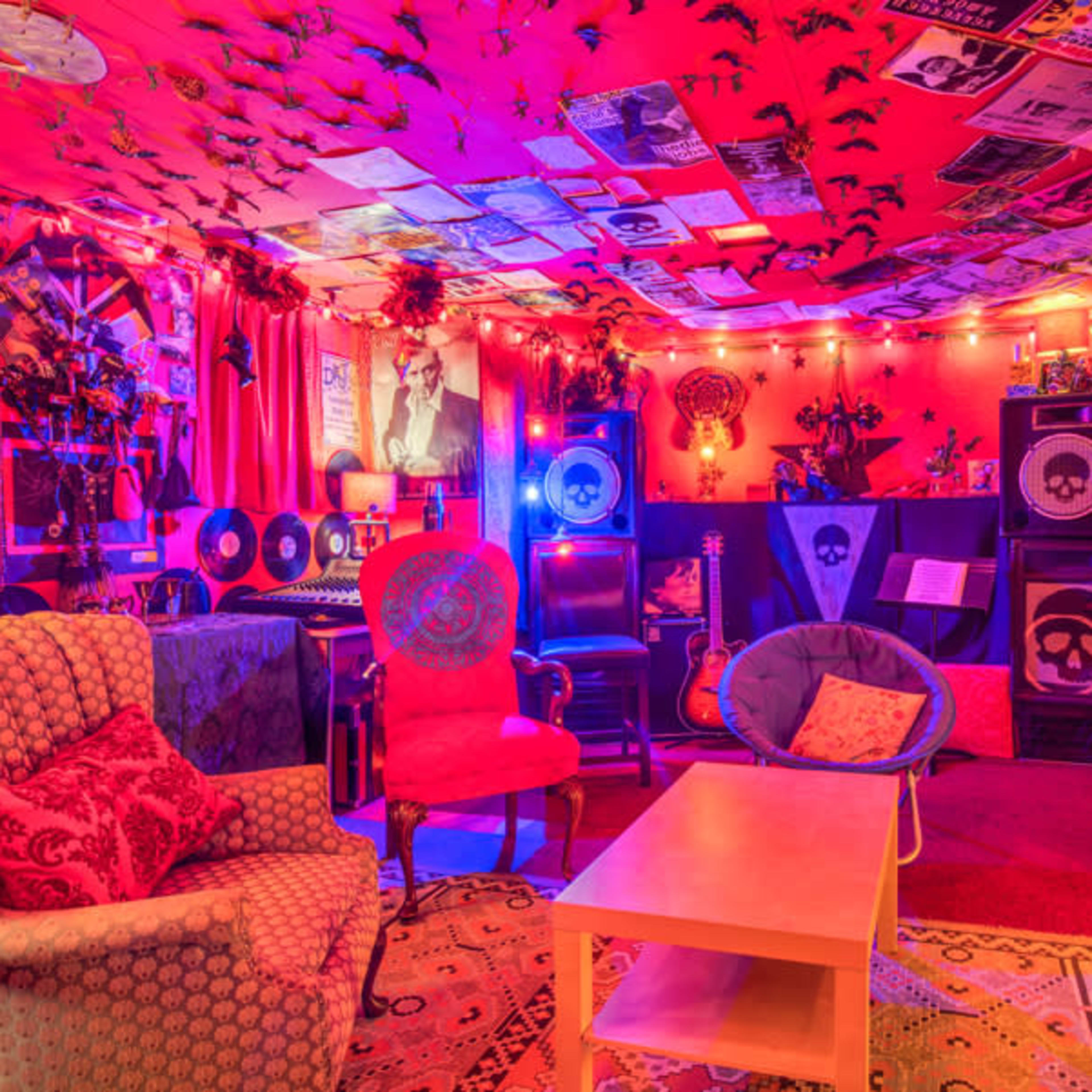 A vibrant, creatively decorated room with colorful walls, eclectic furniture, and various music-related items displayed throughout.