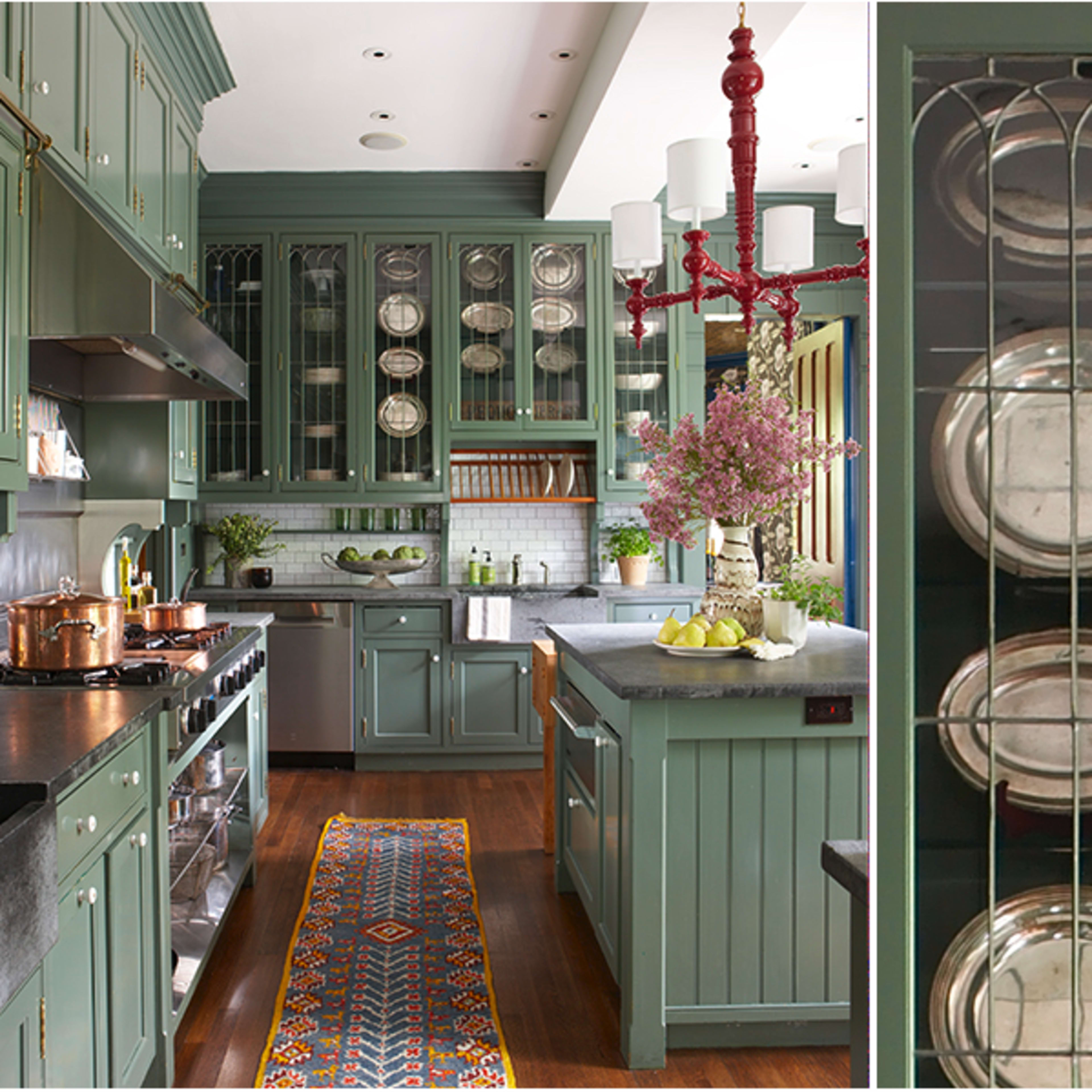 A kitchen with green cabinetry, a central island, and a decorative display of plates in glass-fronted cabinets.