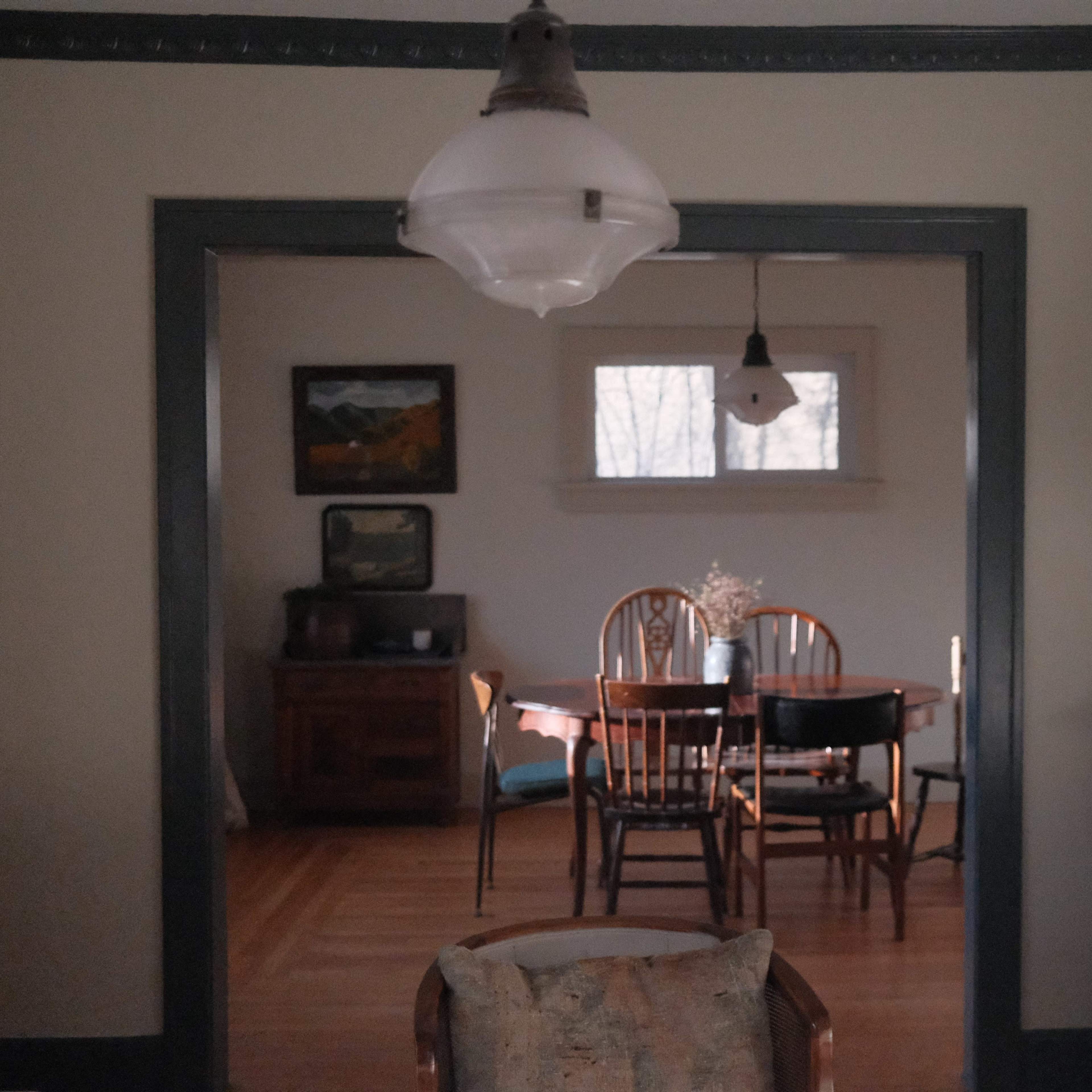 A dining room with a wooden table and chairs is visible through an archway, illuminated by natural light coming through a window.