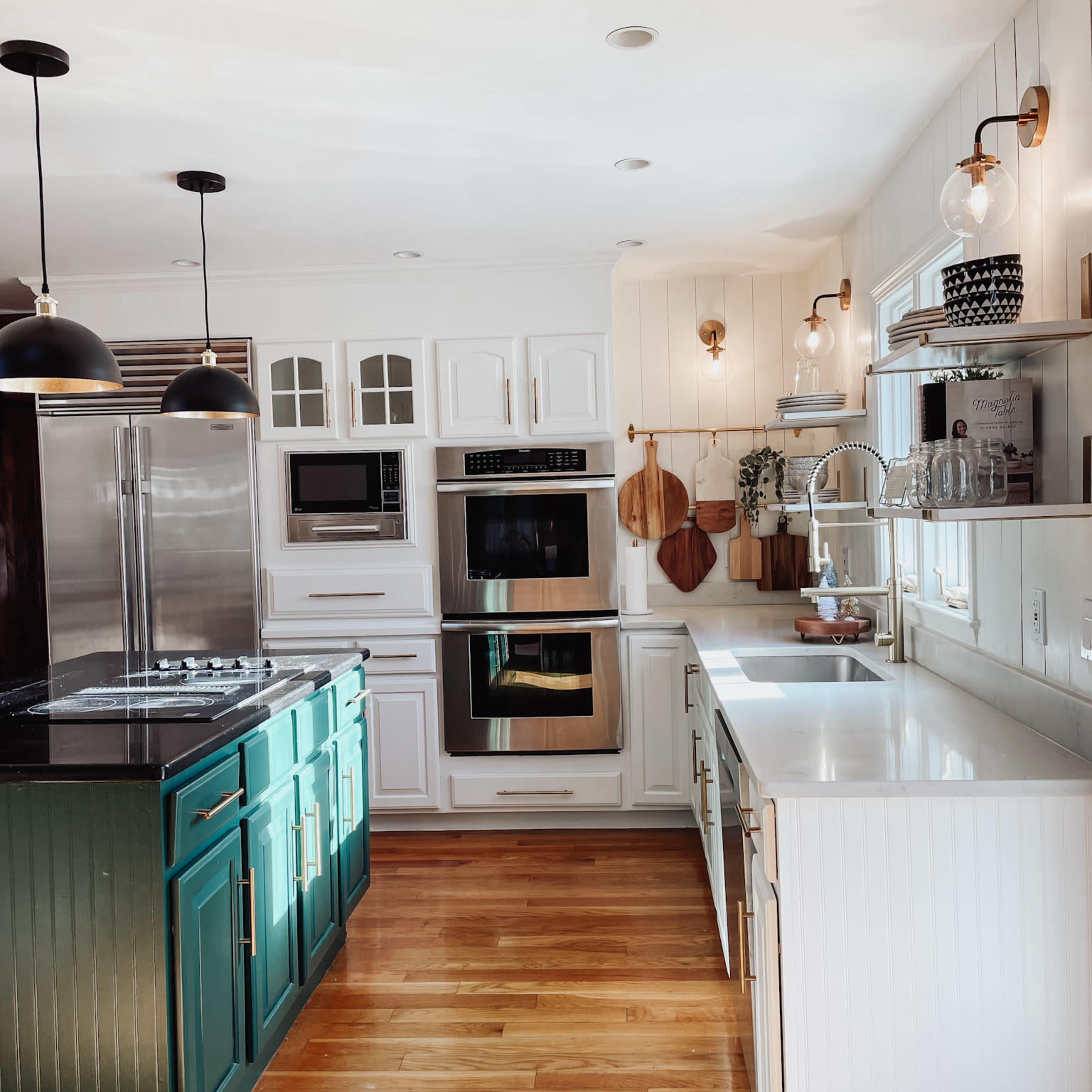 The kitchen features white cabinetry, green lower cabinets, stainless steel appliances, and a light wood floor.