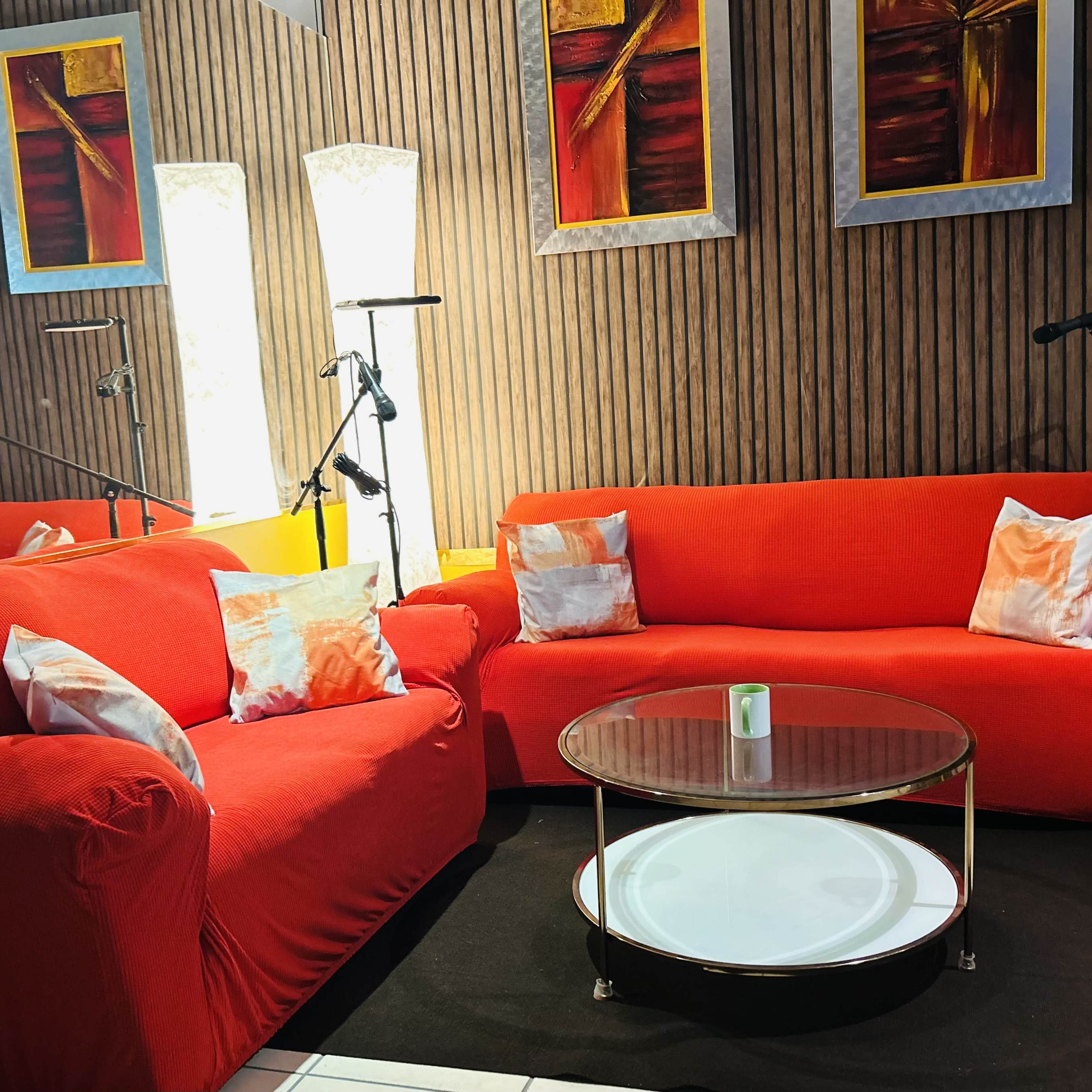 A cozy seating area with two red sofas, a round glass coffee table, and artistic wall decorations.