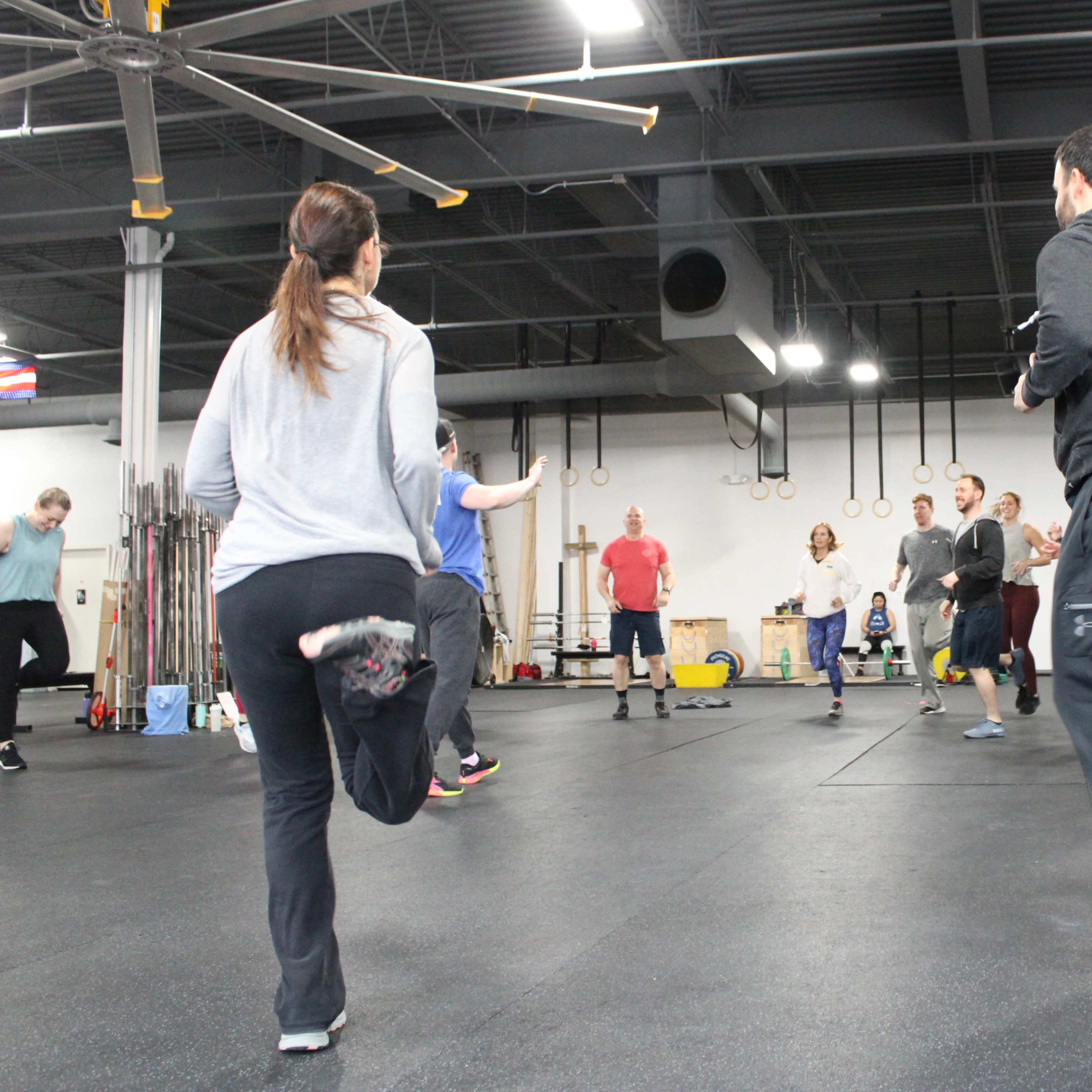 A group of people is exercising in a gym, participating in a workout session.