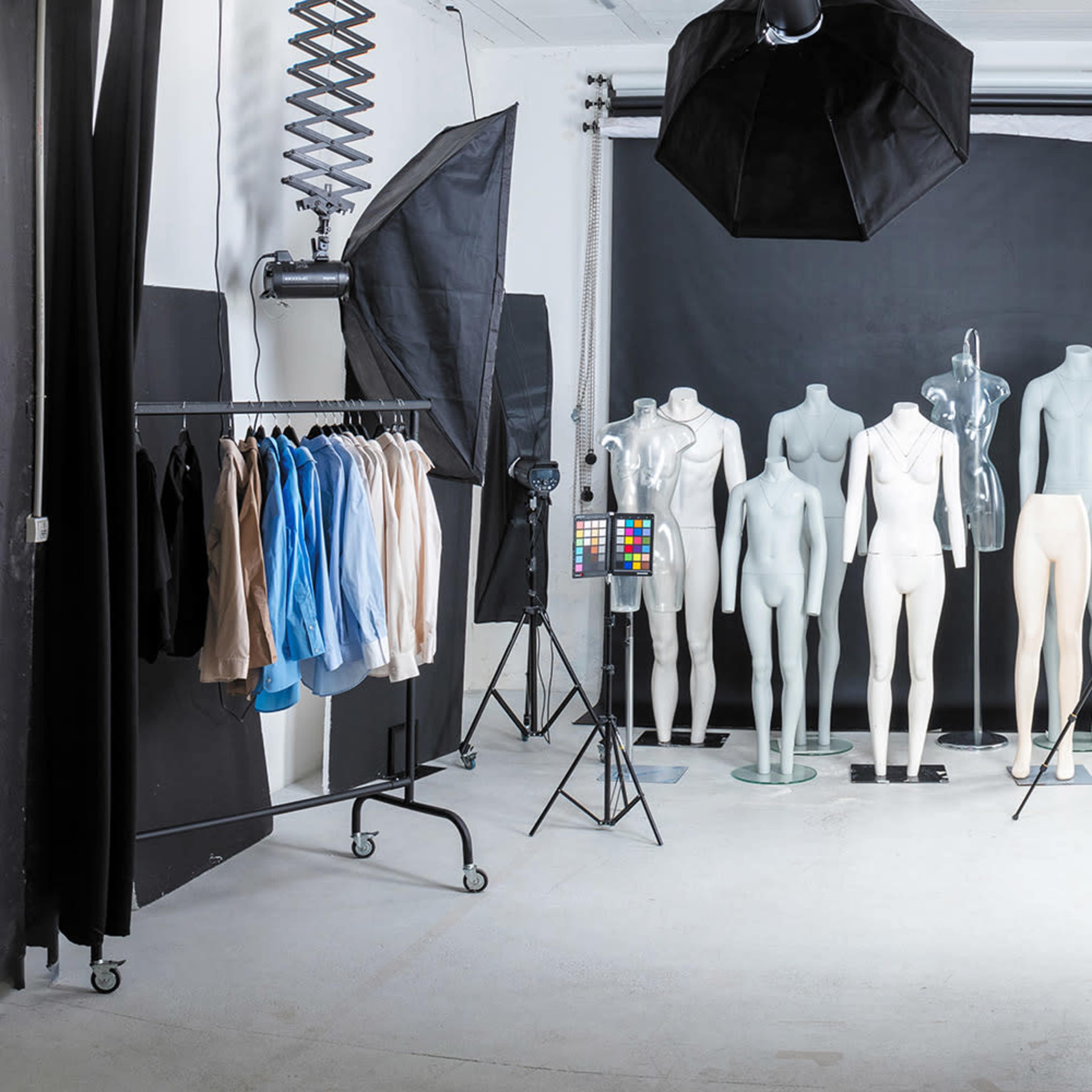 A photography studio equipped with multiple mannequins, lighting equipment, and a clothing rack with various garments.