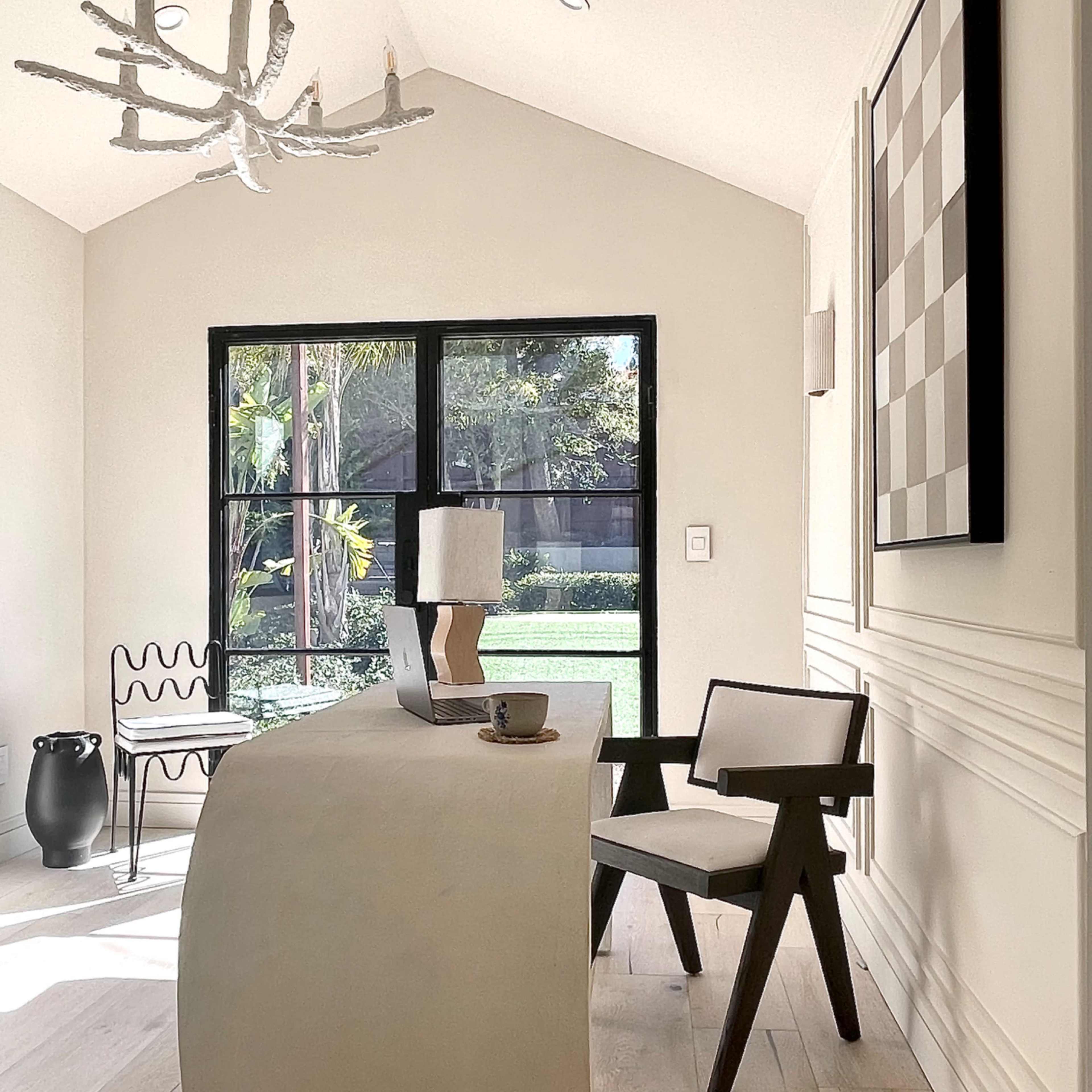 A minimalistic home office features a curved desk, a modern chair, and a large window overlooking a garden.