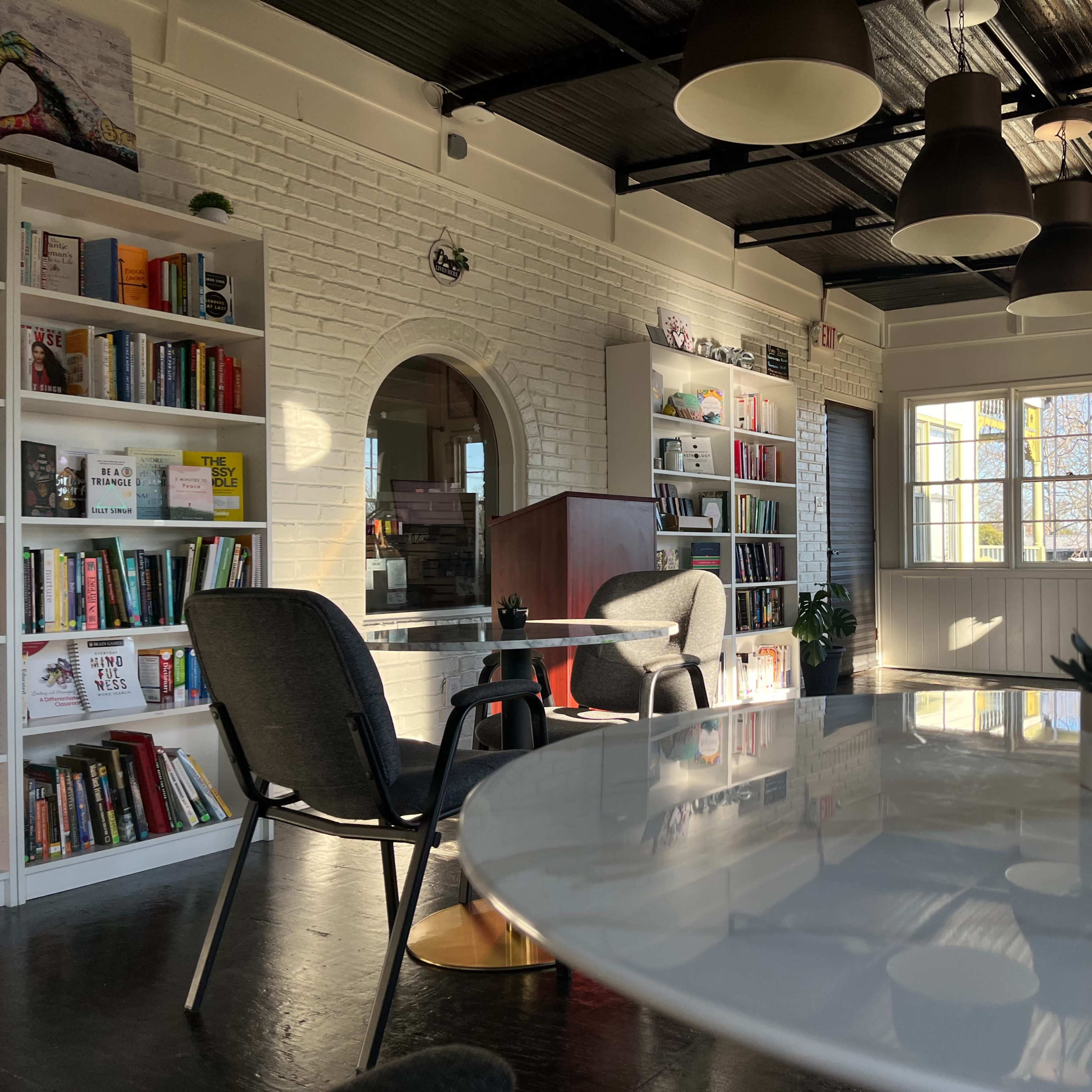 A bright, modern interior of a cozy reading or study space with bookshelves, tables, and chairs.