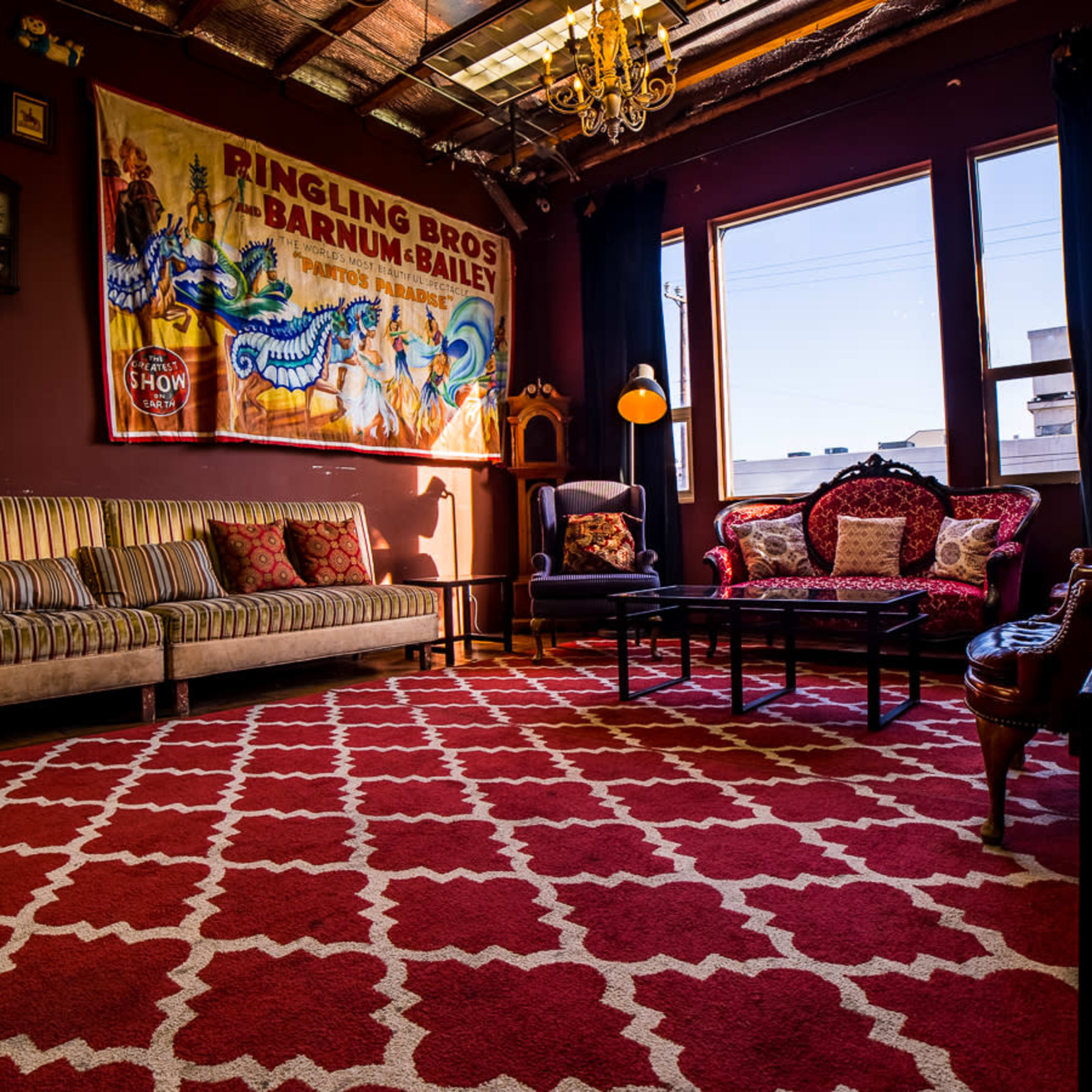 A cozy room with vintage decor, featuring two sofas, a coffee table, and a large wall banner from the Ringling Bros. and Barnum & Bailey Circus.
