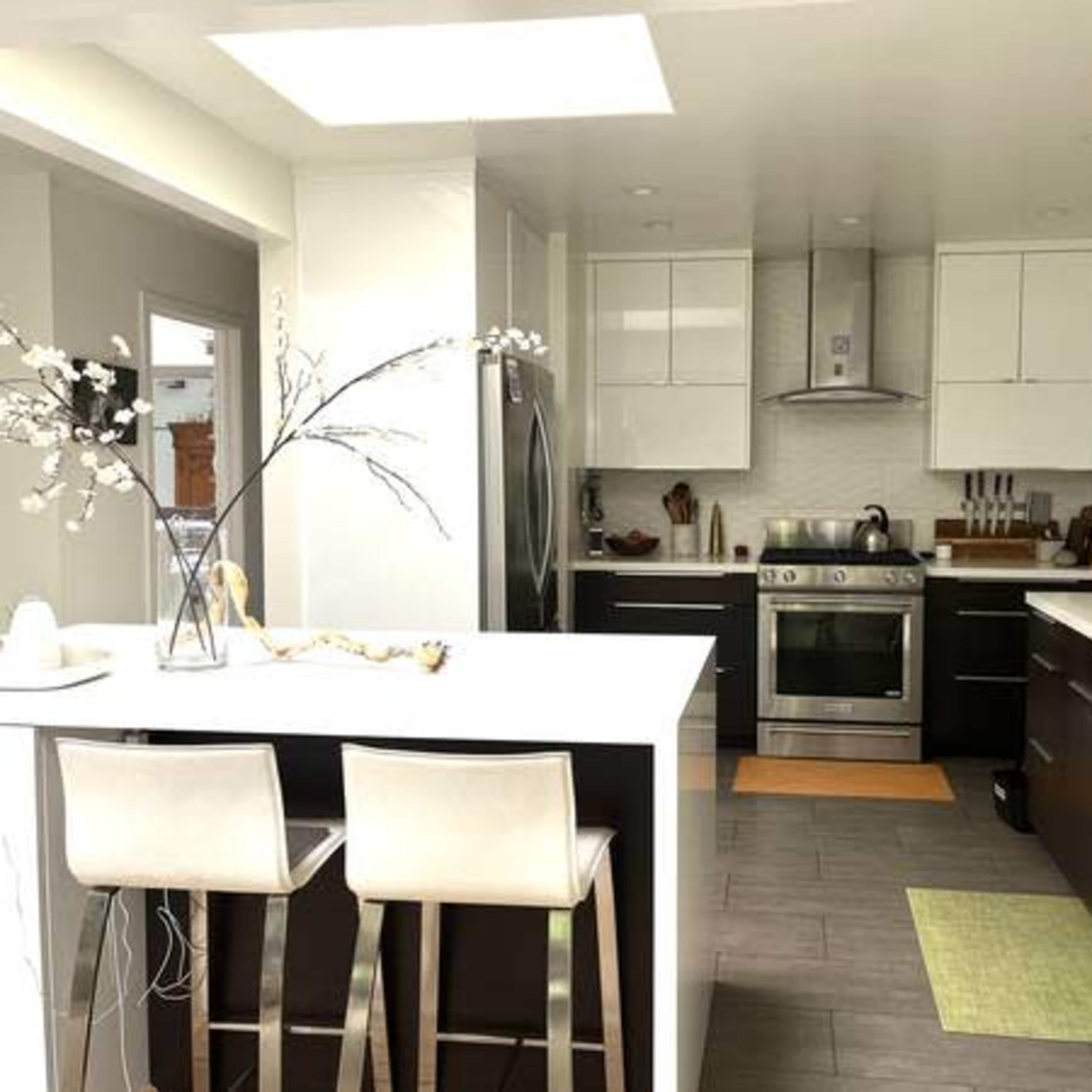 A modern kitchen with sleek cabinetry, stainless steel appliances, and an island with two bar stools.