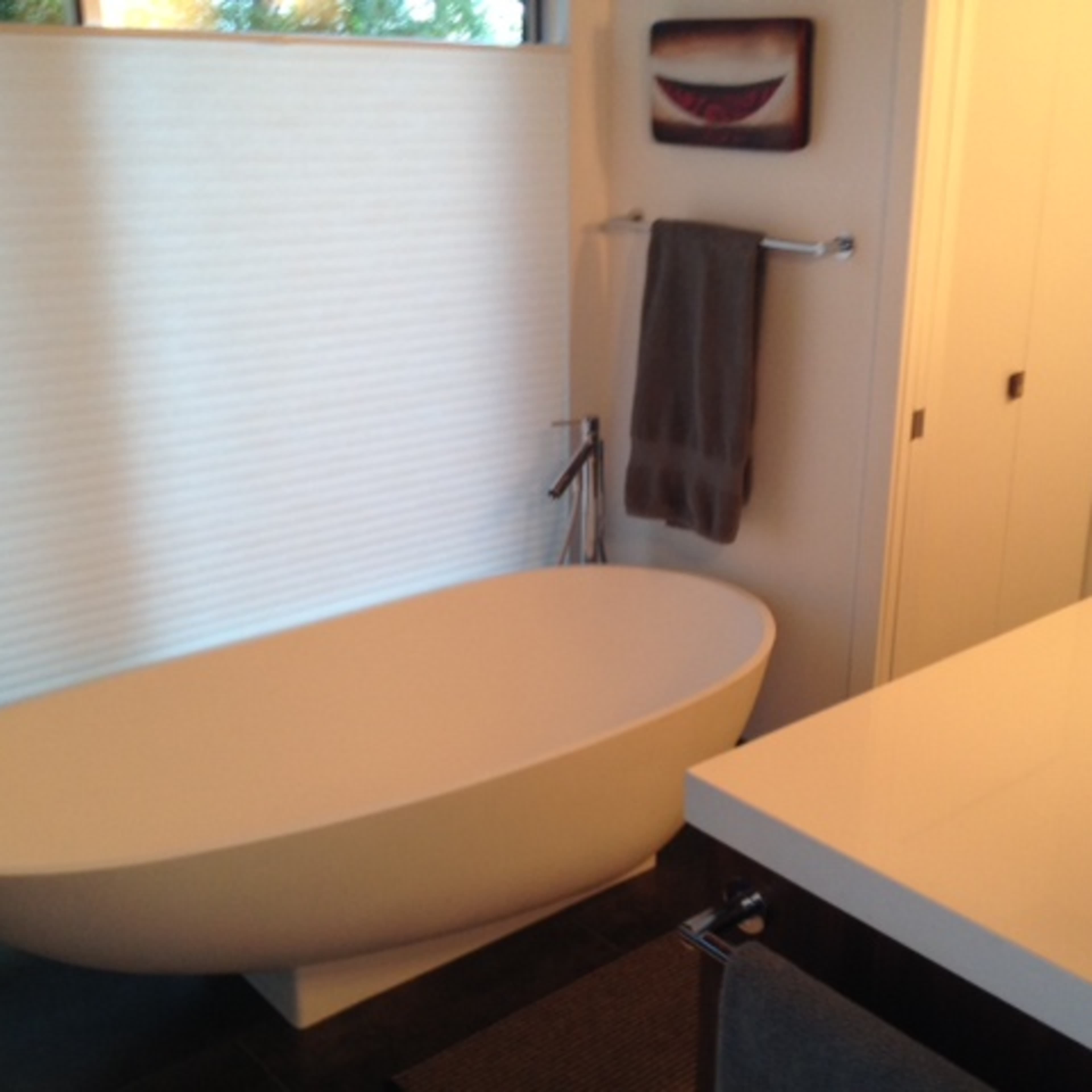 A modern bathroom featuring a freestanding oval bathtub, a wall-mounted towel rack, and a countertop sink with minimalistic design elements.