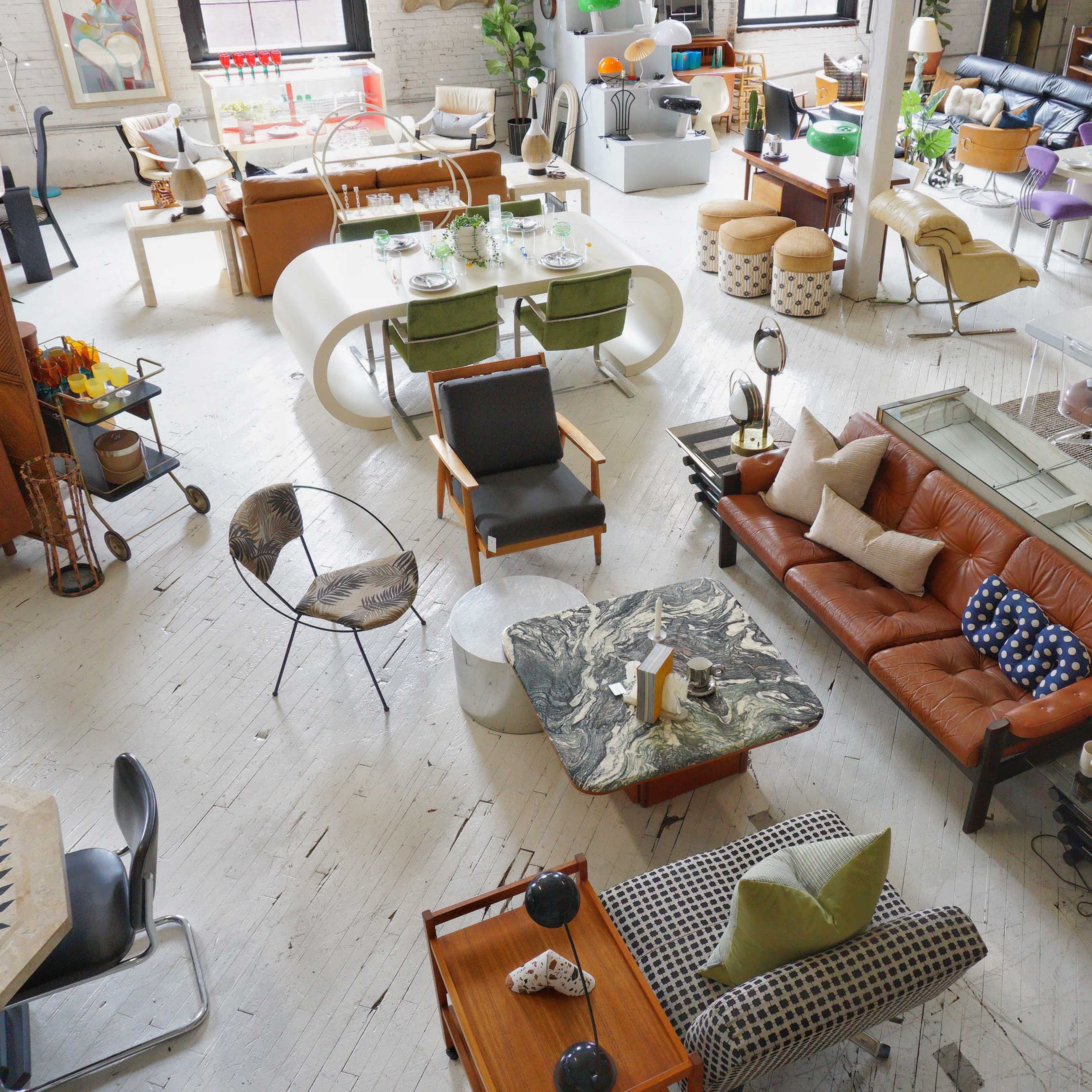 An interior space filled with various pieces of modern furniture, including seating, tables, and decorative items, arranged in an open layout.