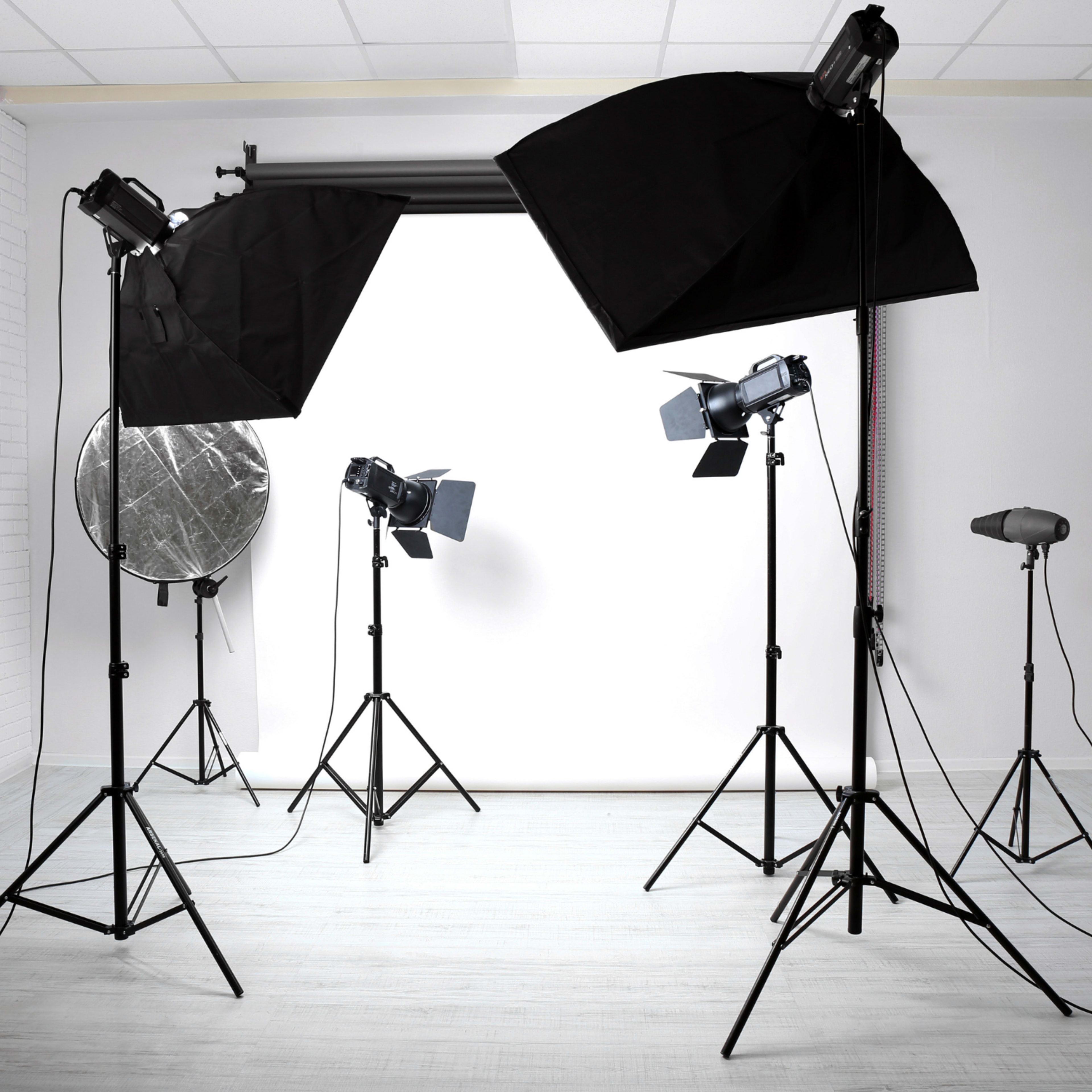 A photography studio equipped with multiple lighting setups and a blank backdrop.