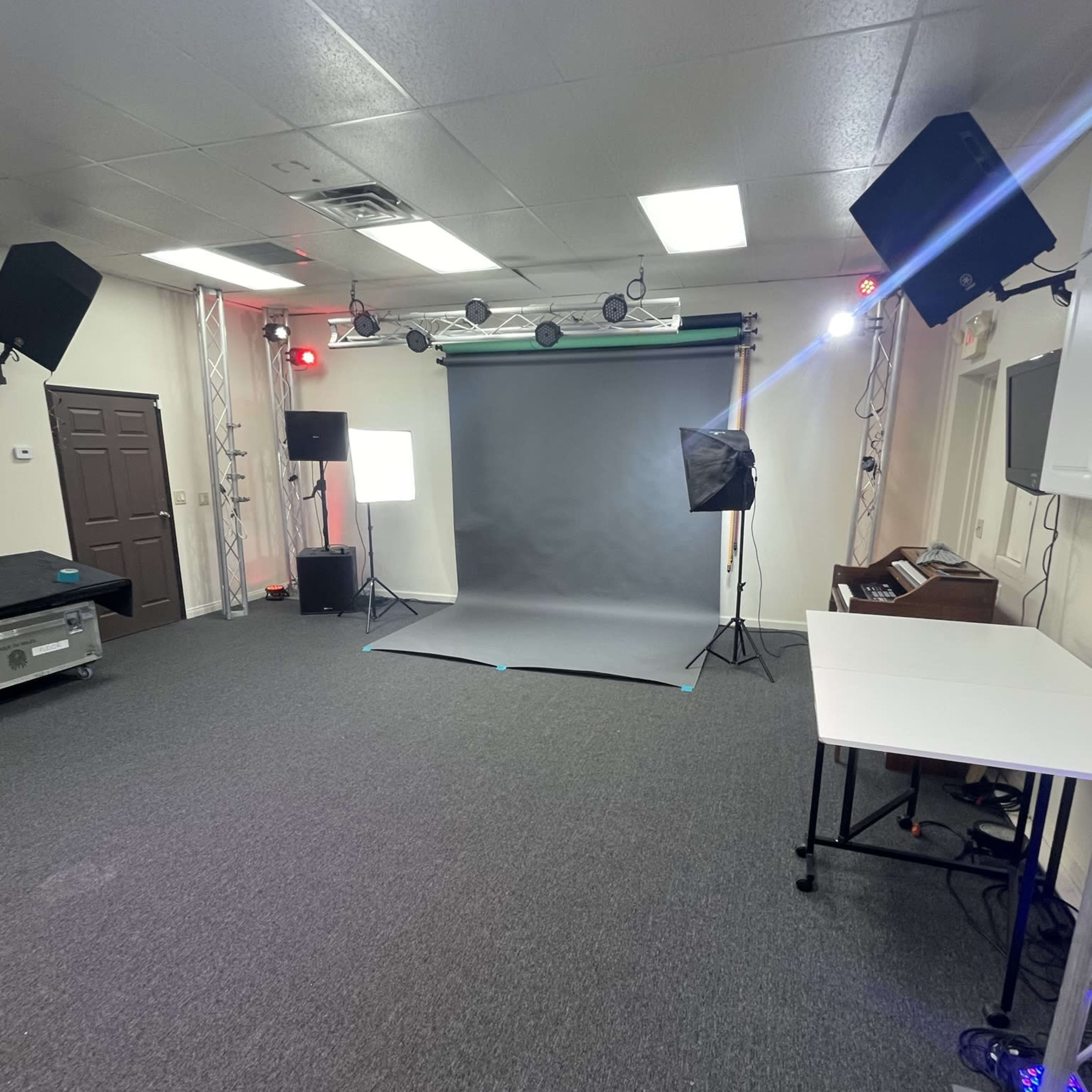 A studio space featuring a gray backdrop, multiple lighting setups, and a table in an uncluttered environment.