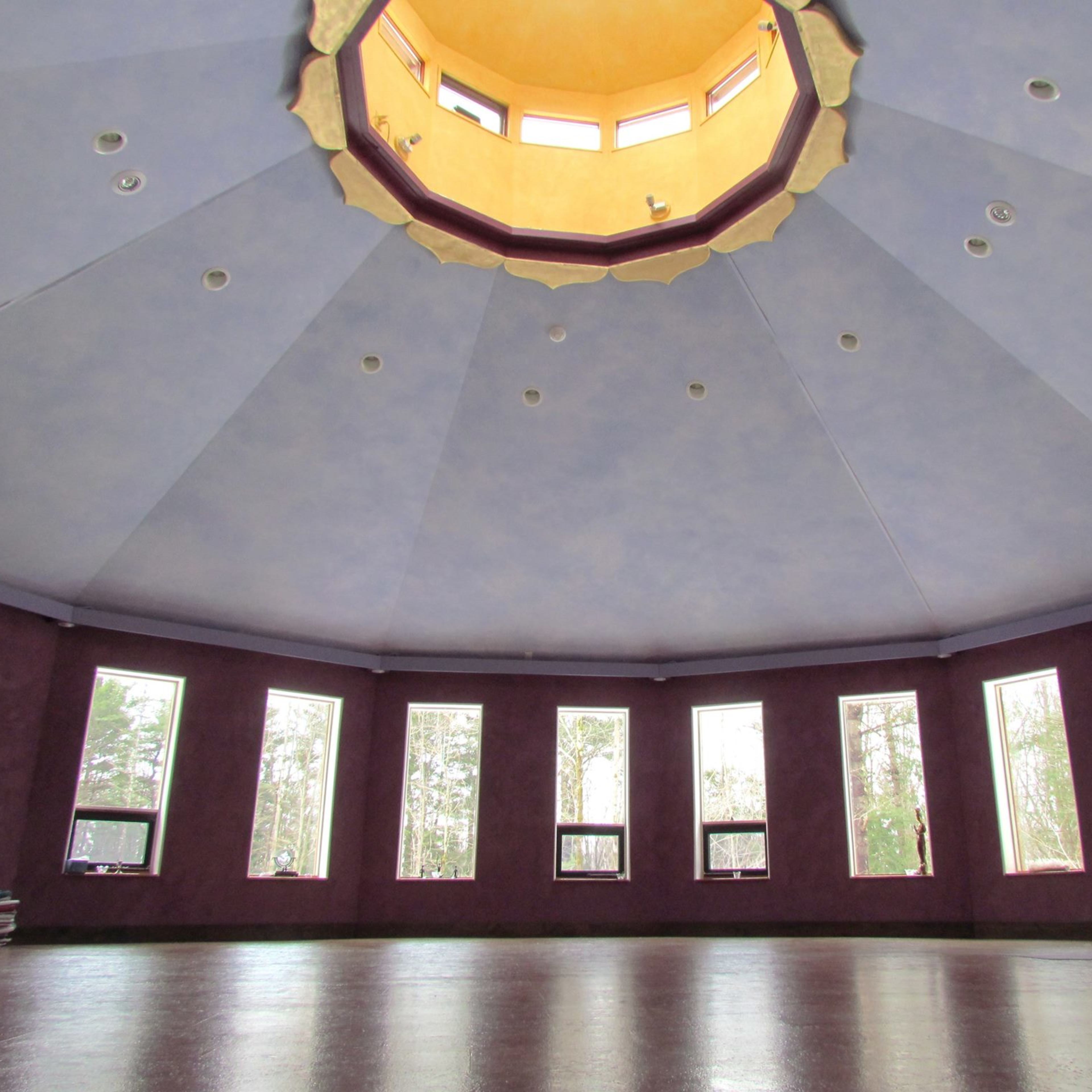 The interior of a circular room with a domed ceiling and multiple windows around the walls.