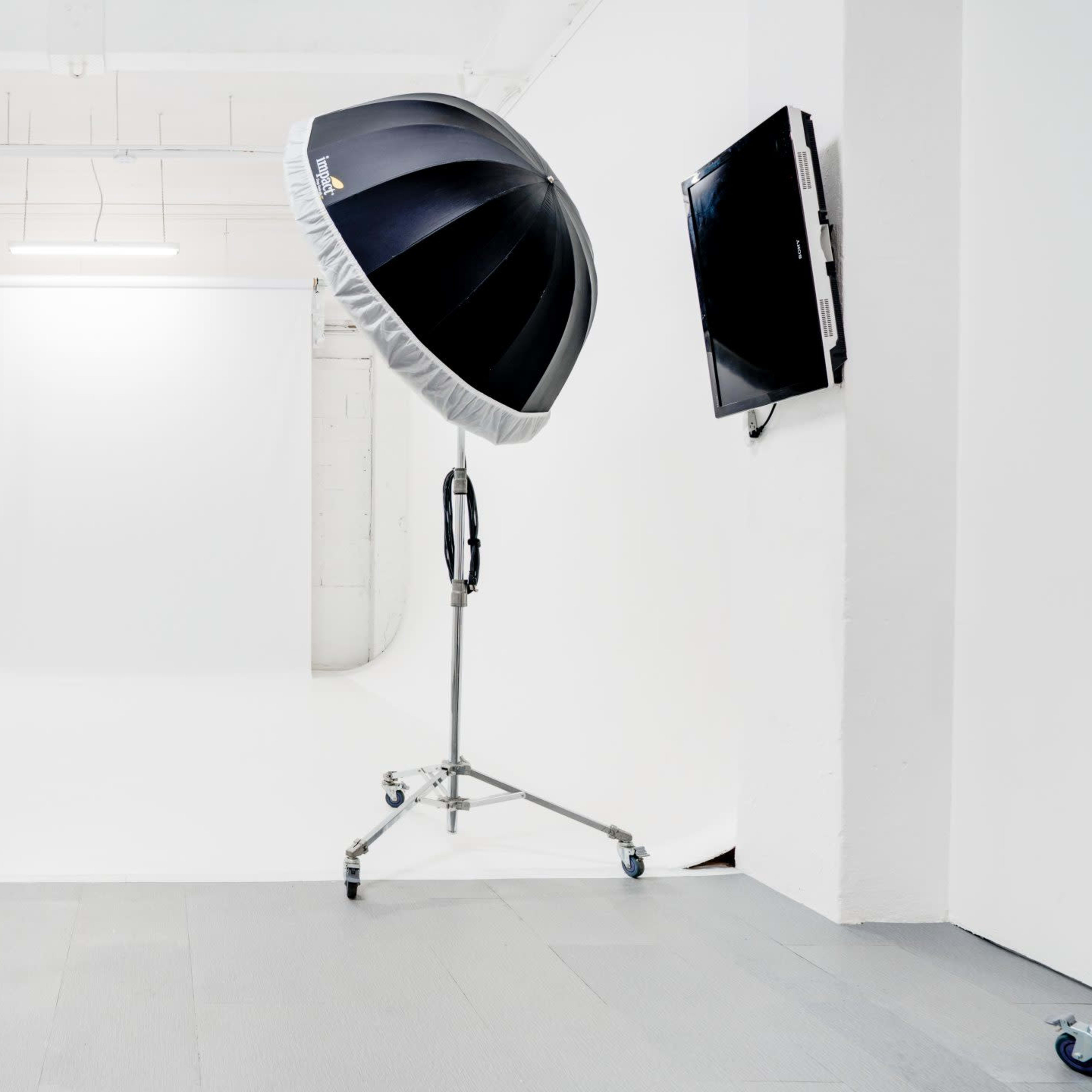 A photography studio with two large softboxes positioned on stands facing a plain white backdrop.