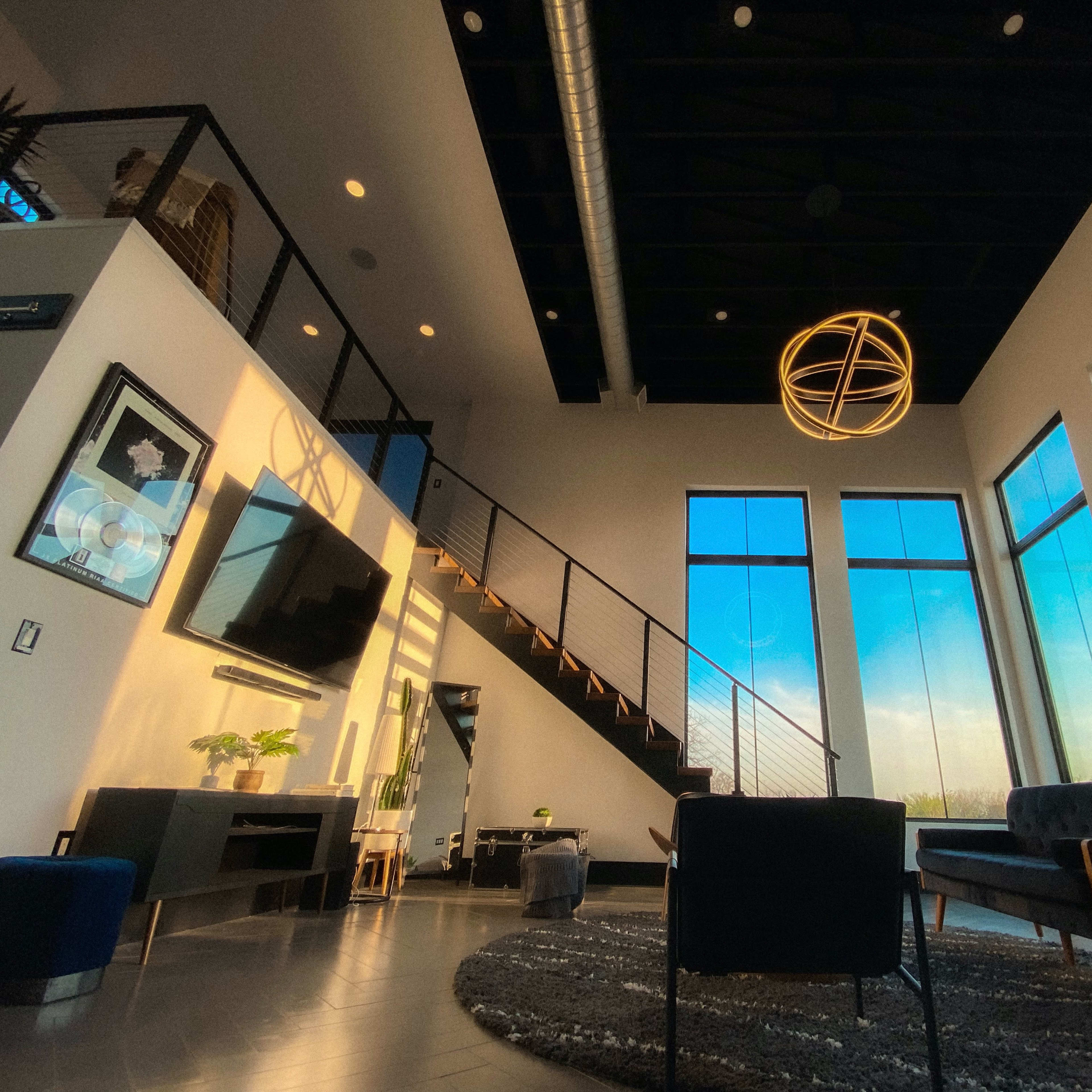 A modern living room features large windows, a spiral staircase, and contemporary furniture.