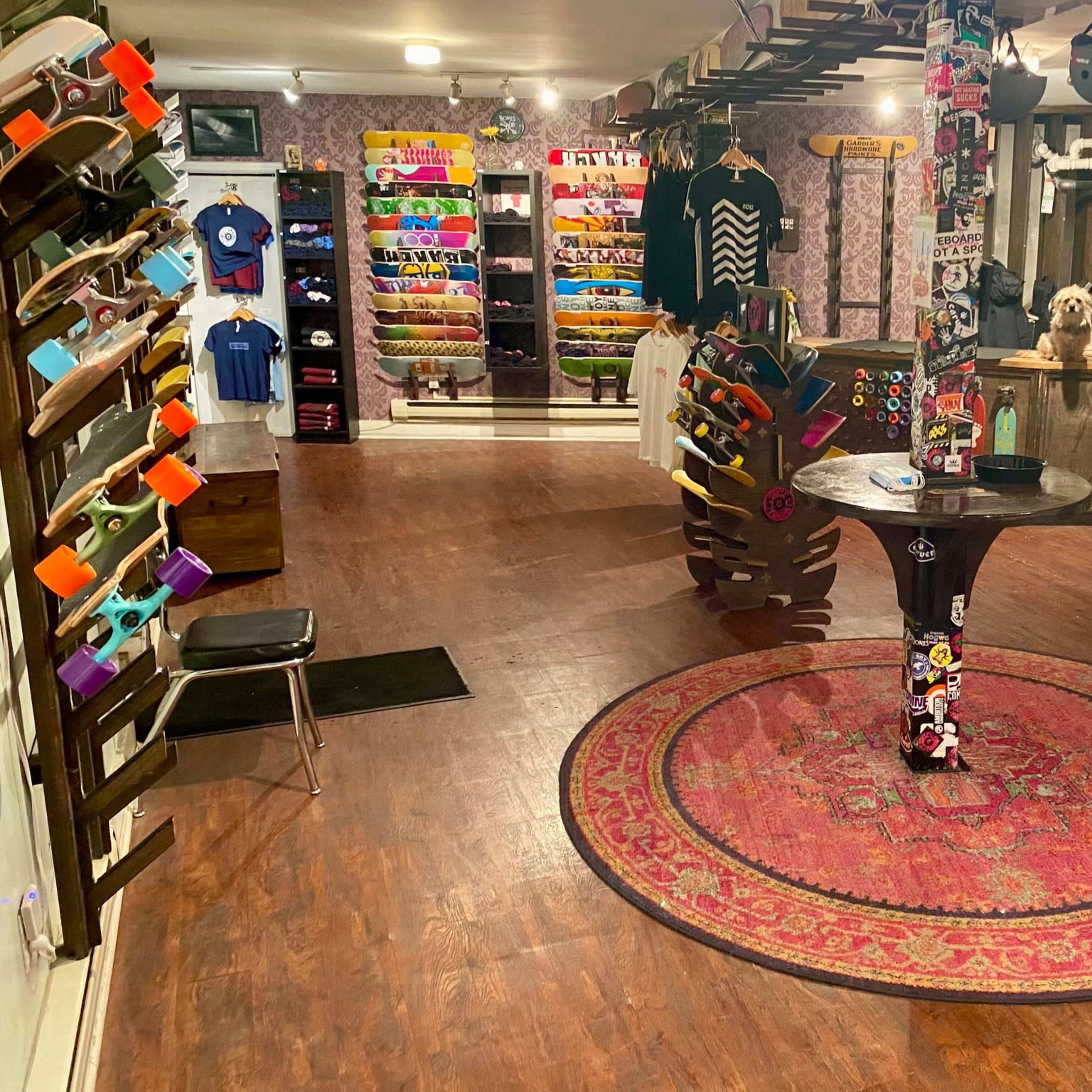The interior of a skate shop featuring rows of skateboards, apparel, and accessories displayed on racks against a patterned wall.