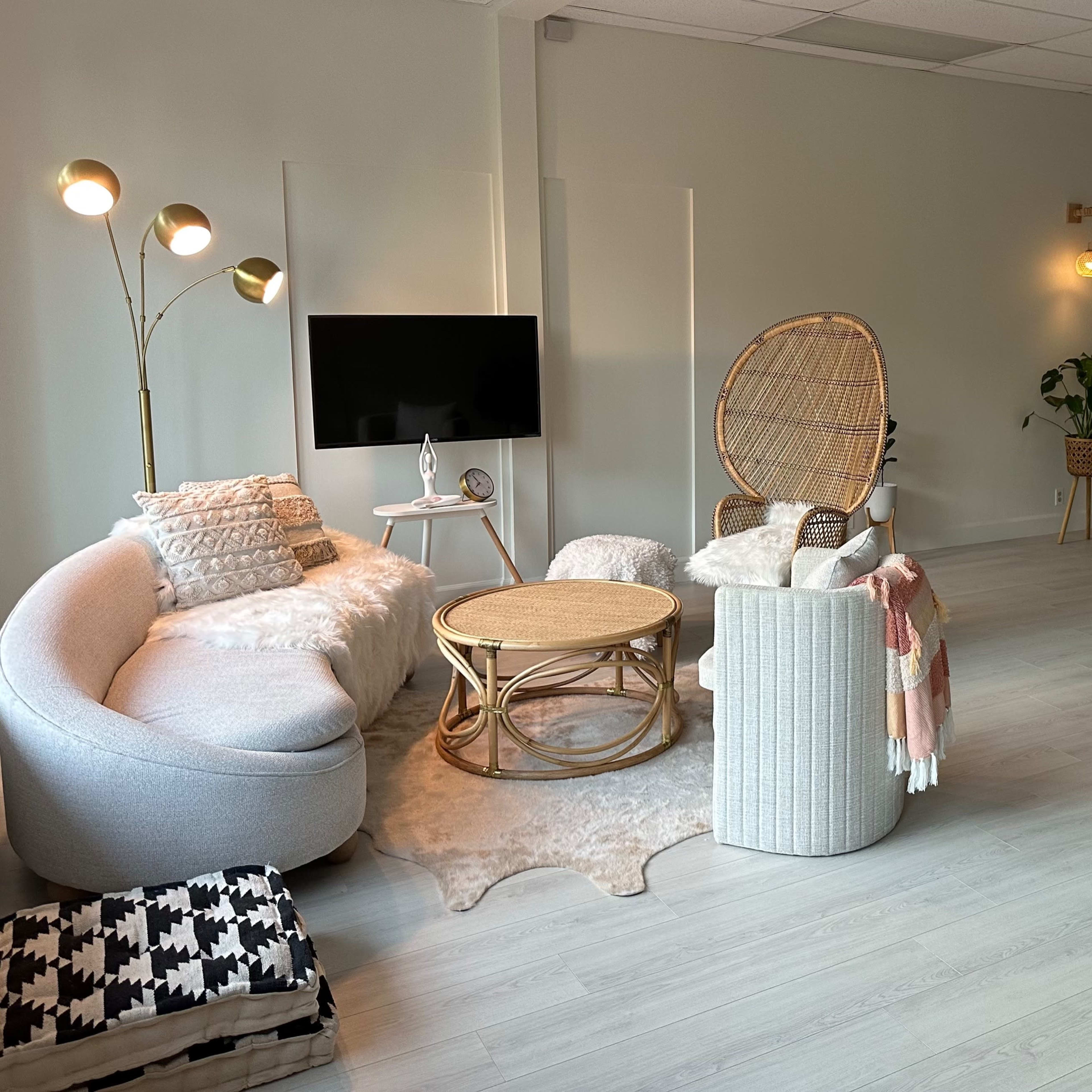 A spacious, softly lit room with comfortable seating, a television, and various plants, creating a relaxed atmosphere.