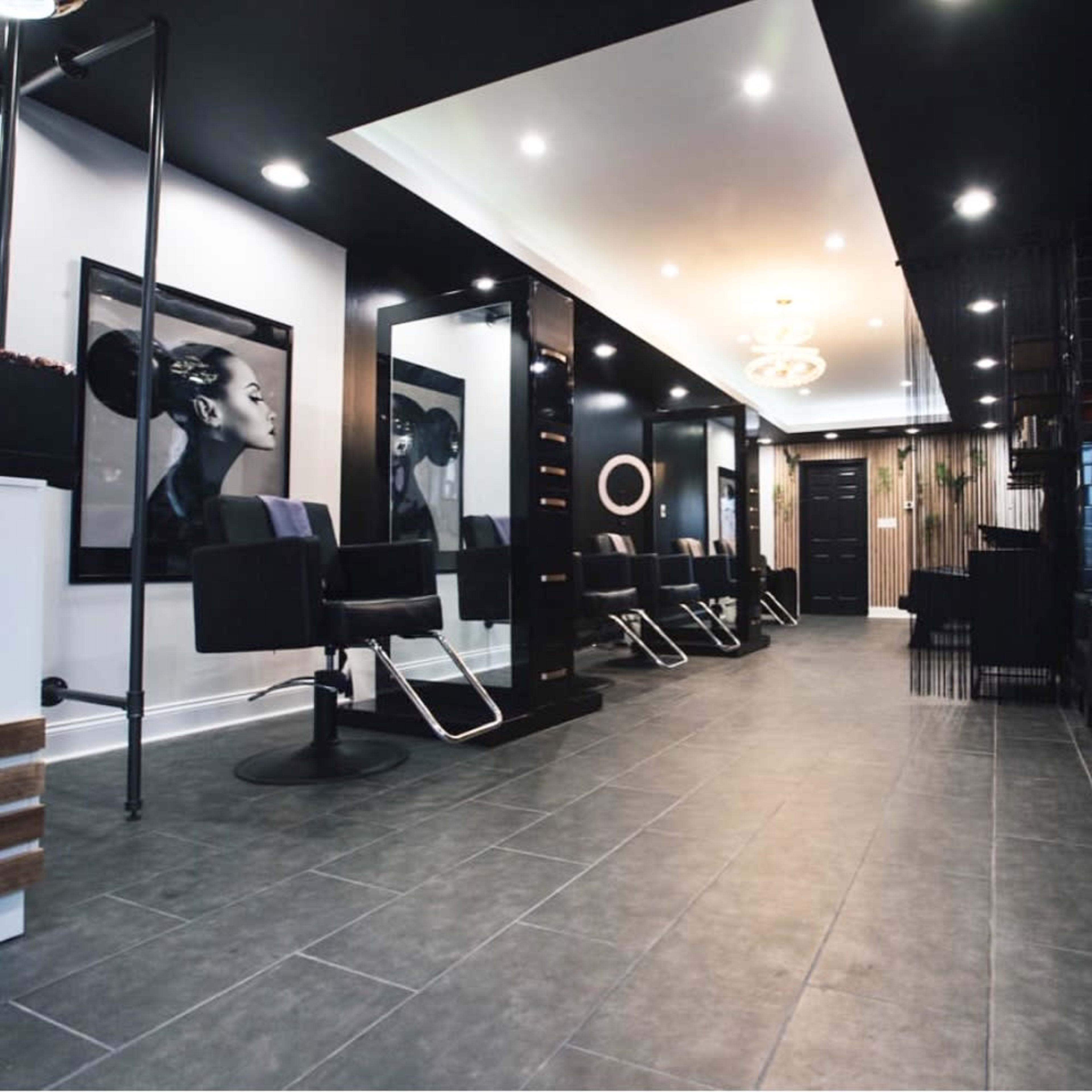 A modern hair salon with sleek black walls, stylish chairs, large mirrors, and a well-lit interior.