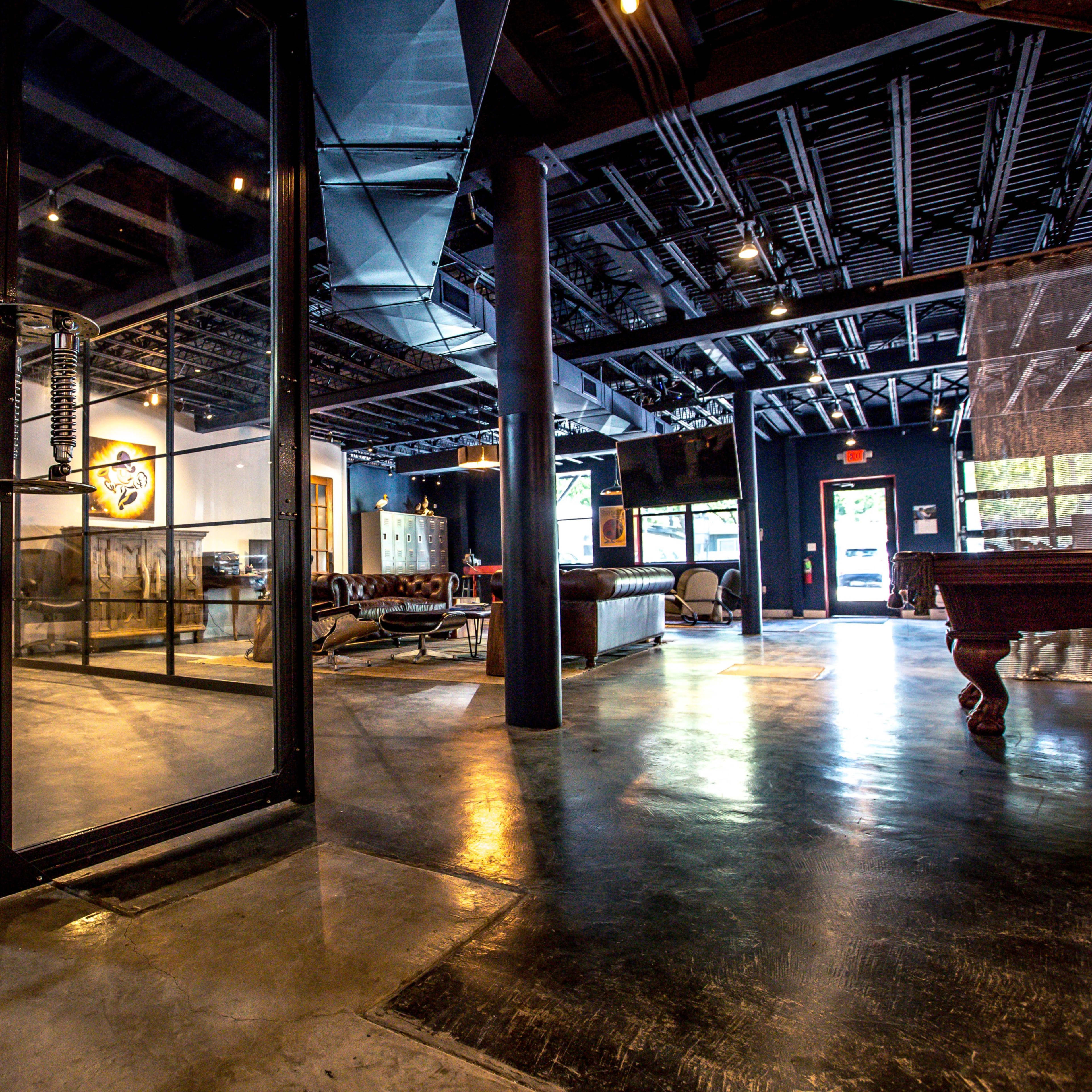 A modern office space featuring glass partitions, meeting areas, seating arrangements, and a pool table.