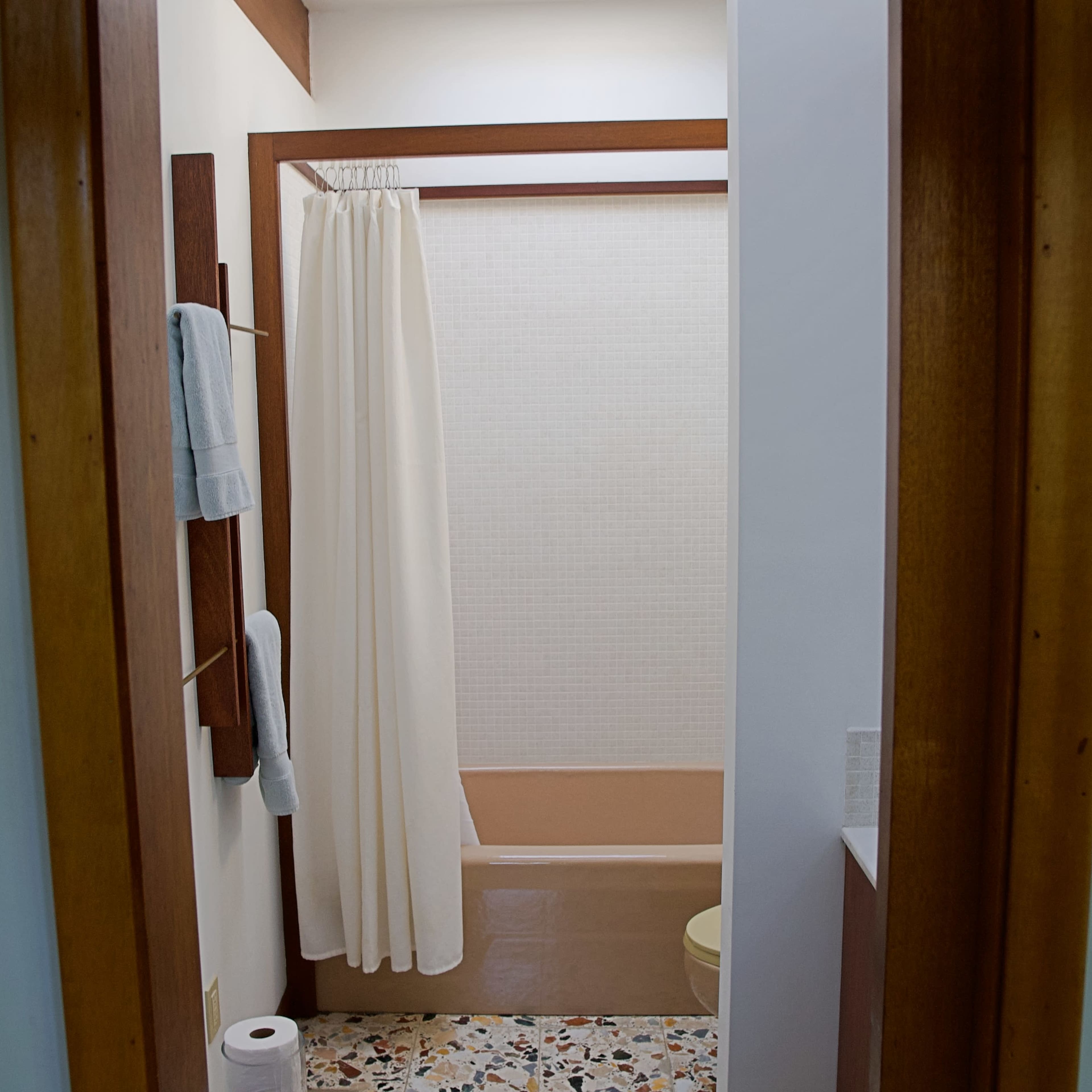 A bathroom scene features a bathtub with a shower curtain, towel racks, and a tiled floor.