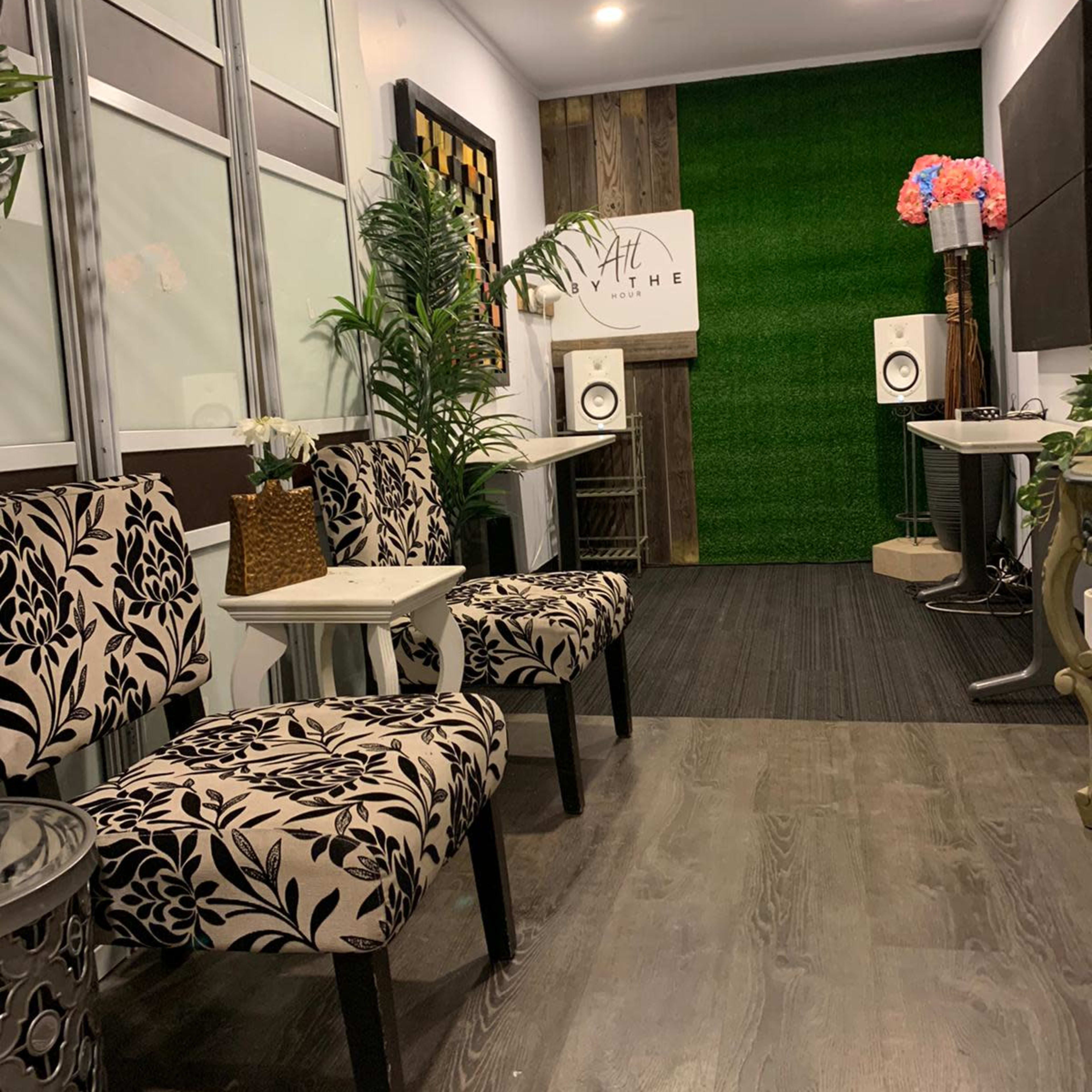 A modern waiting area with patterned chairs, small tables, and greenery on the walls.