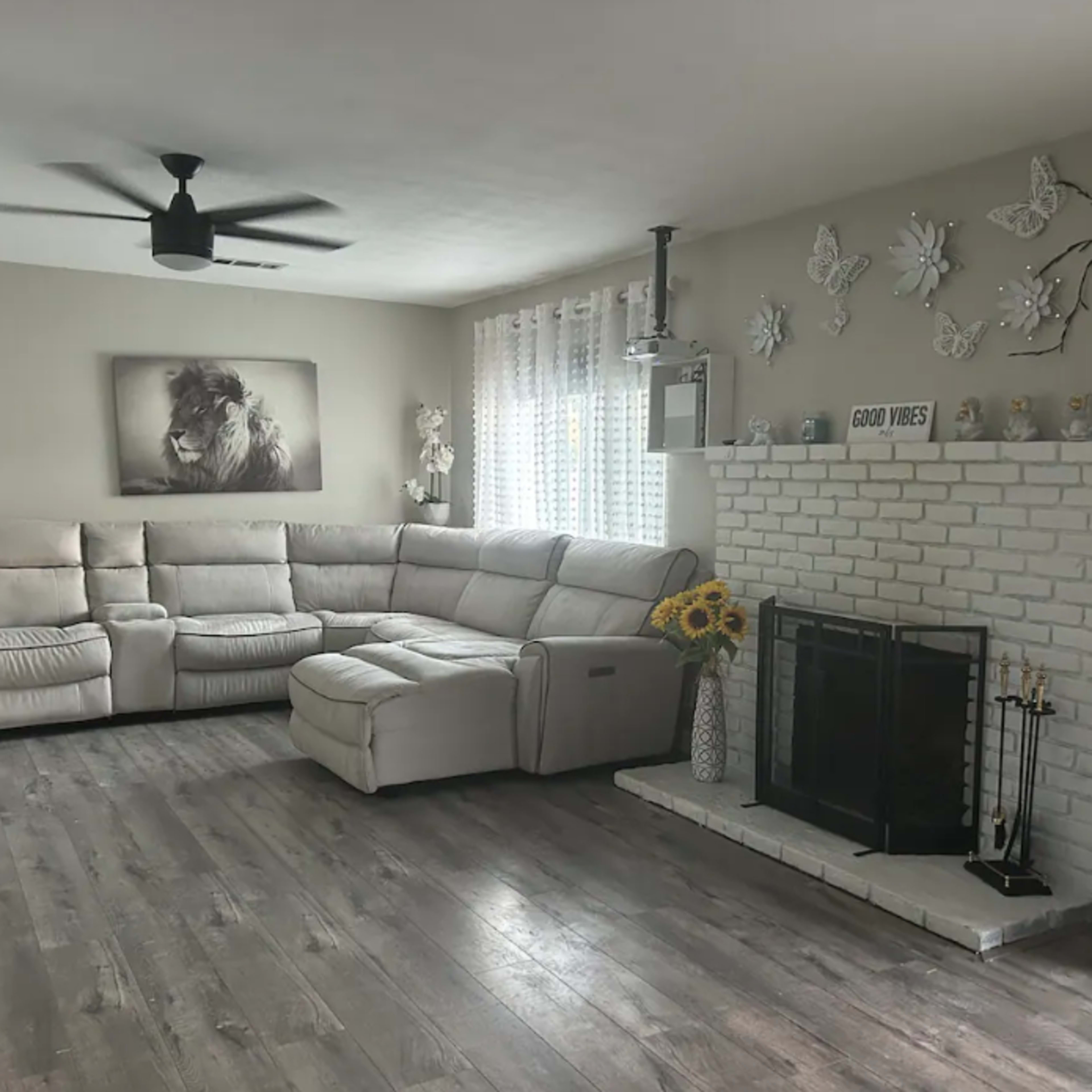 A modern living room with a sectional couch, a stone fireplace, and decorative elements including a lion portrait and sunflowers.