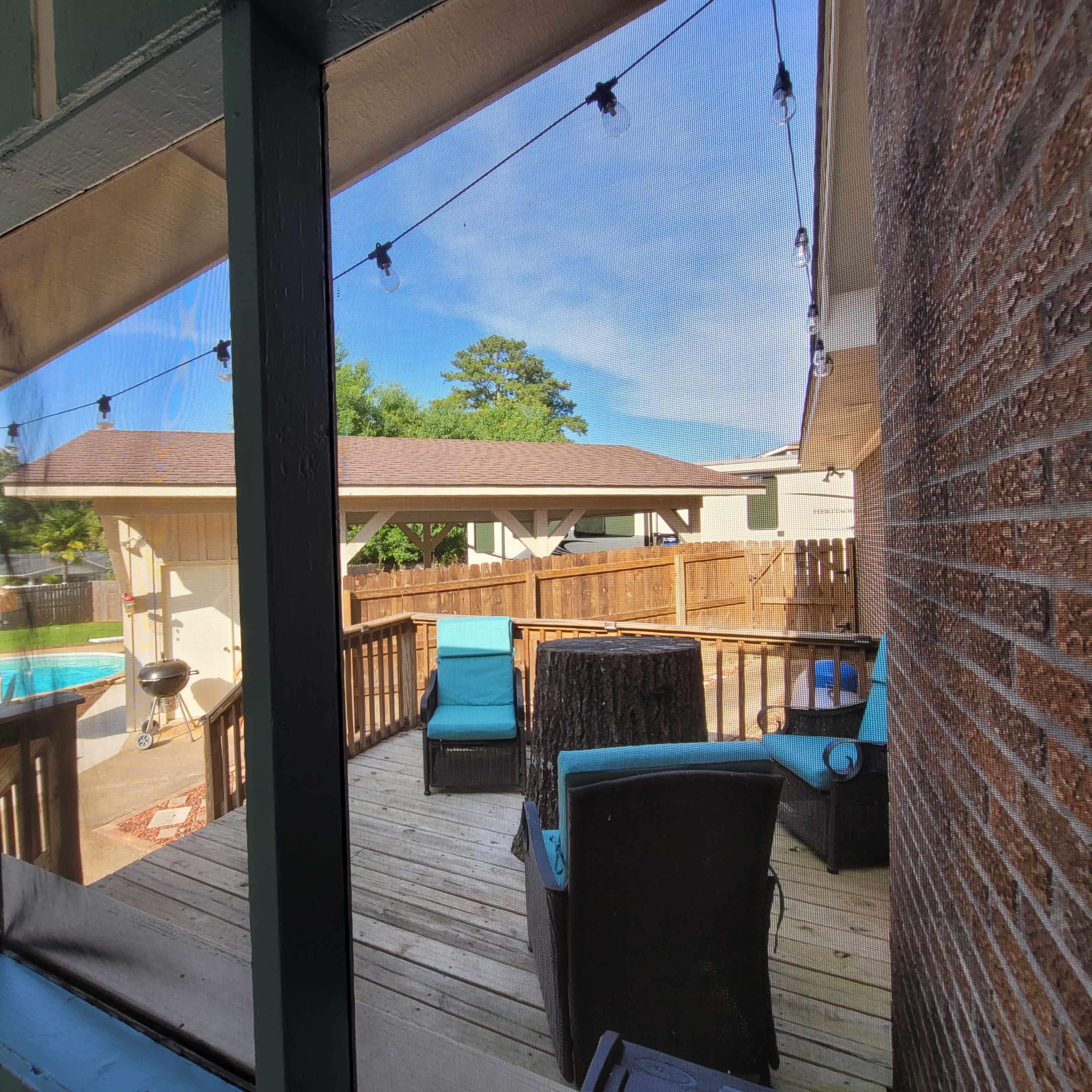 A wooden deck is visible through a screened window, featuring patio furniture and a view of a pool and surrounding yard.