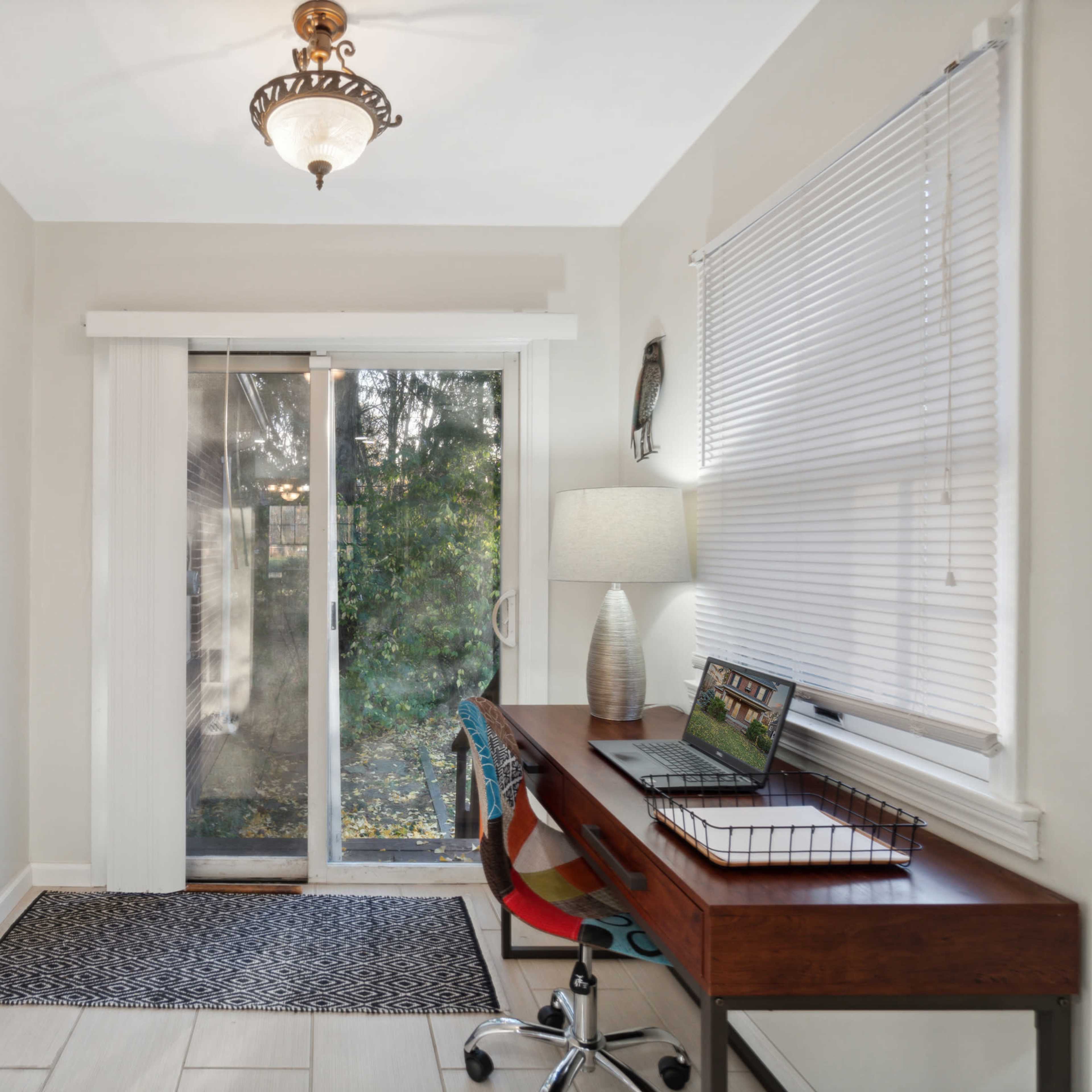 A small home office area with a desk, chair, and sliding glass door leading to an outdoor view.