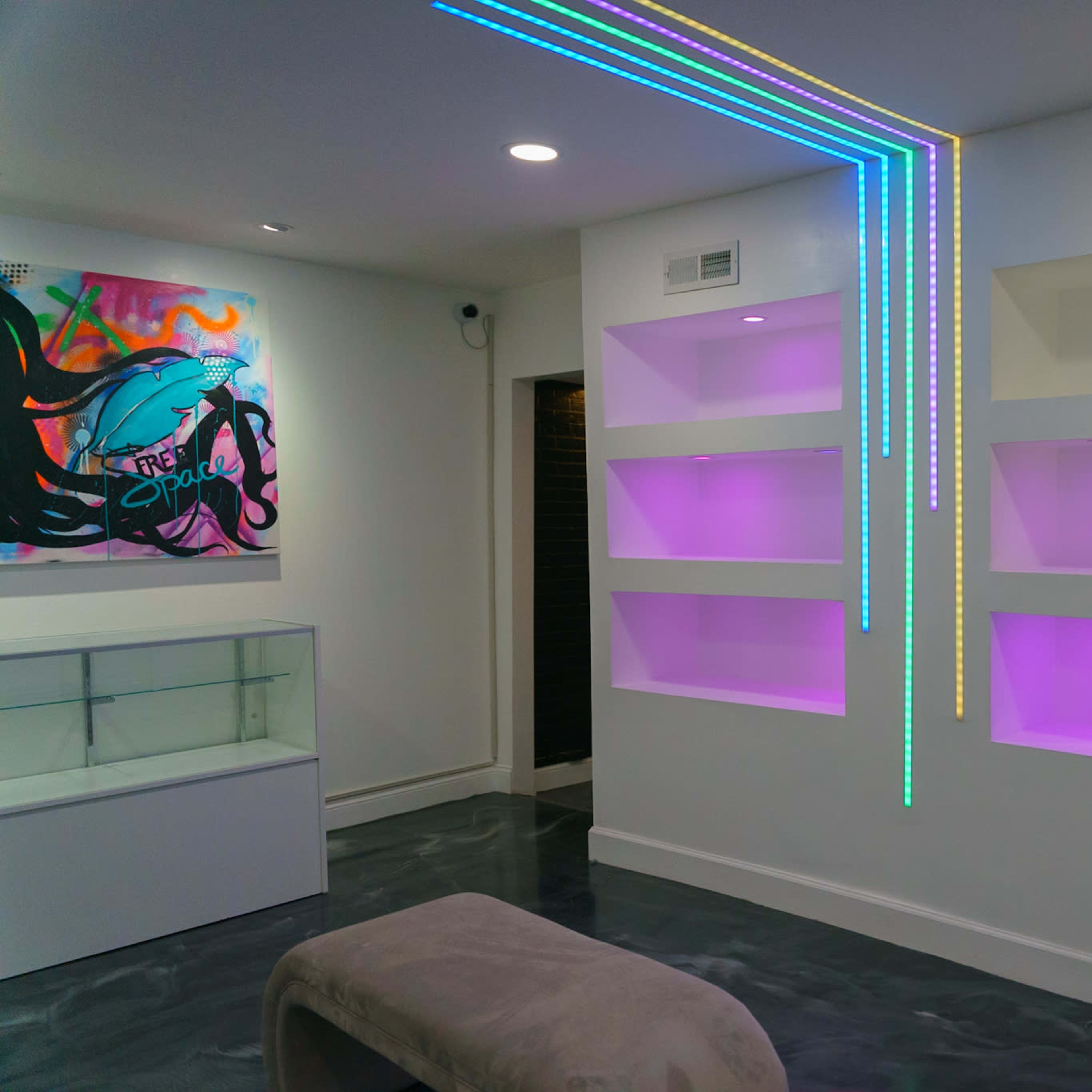A modern interior showcases illuminated shelves and a colorful wall art piece.