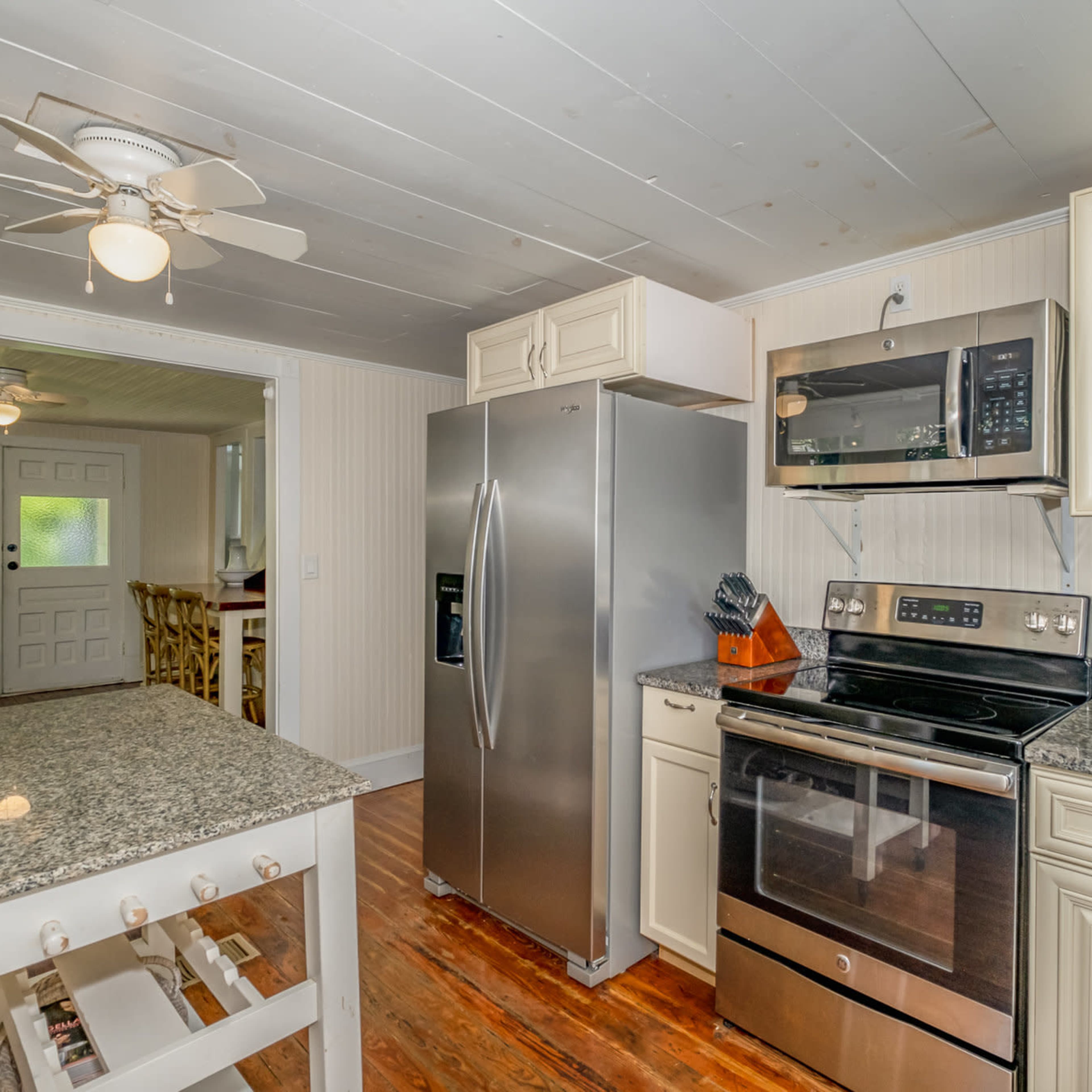 The kitchen features stainless steel appliances, including a refrigerator and oven, with granite countertops and white cabinetry.
