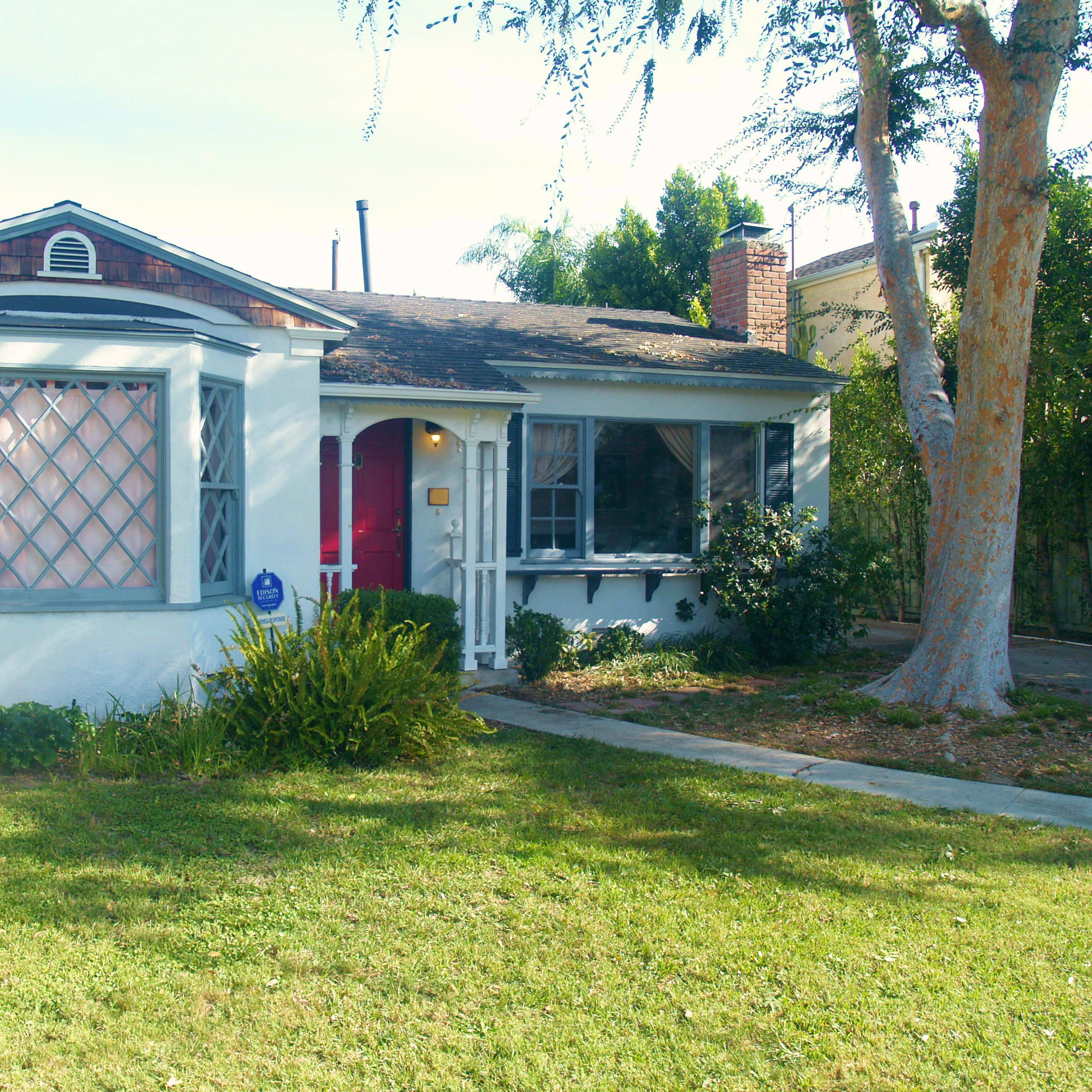 A small, single-story house with a rounded bay window and a well-kept lawn.