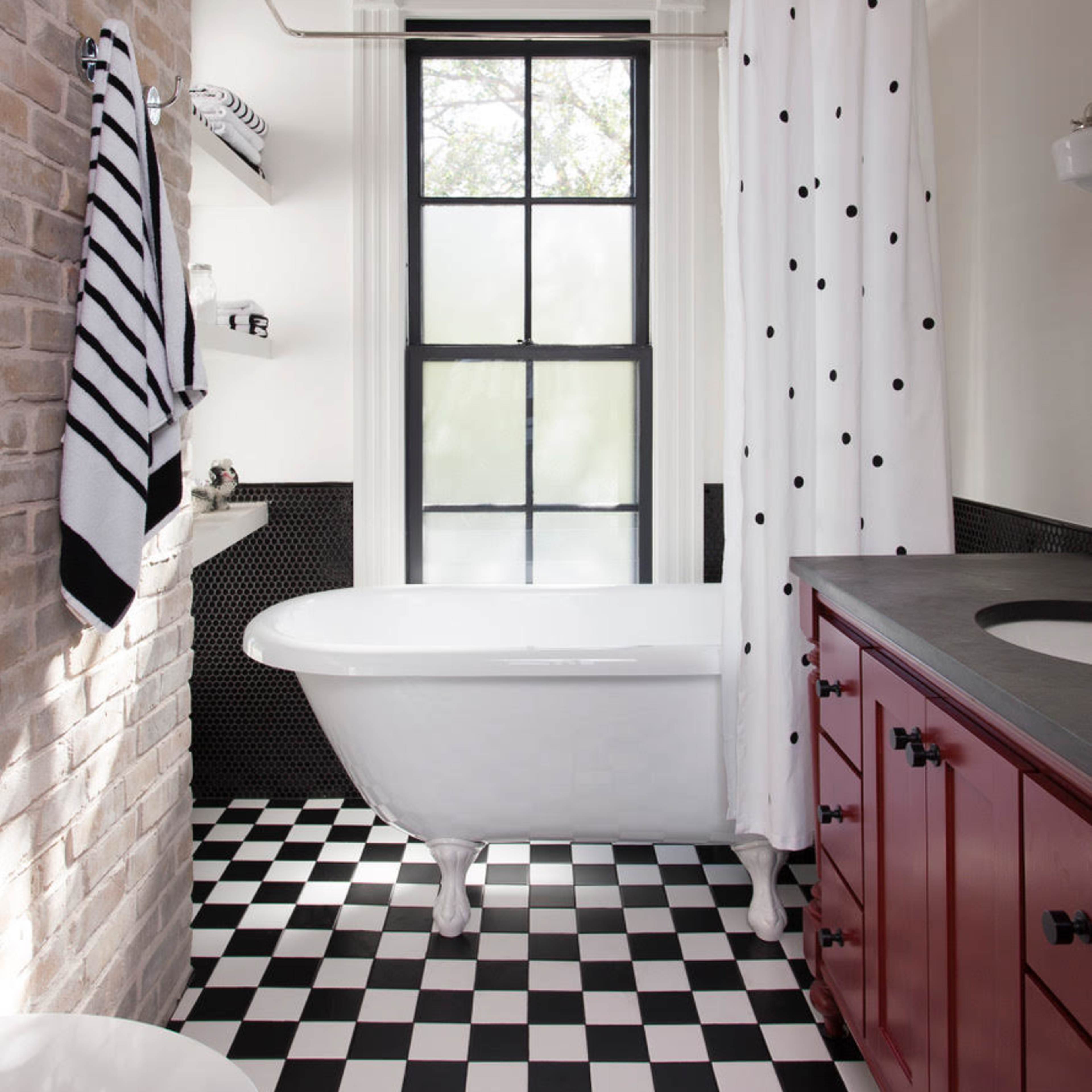 The bathroom features a freestanding white bathtub, a black and white checkered floor, and a window with a black and white polka-dot shower curtain.
