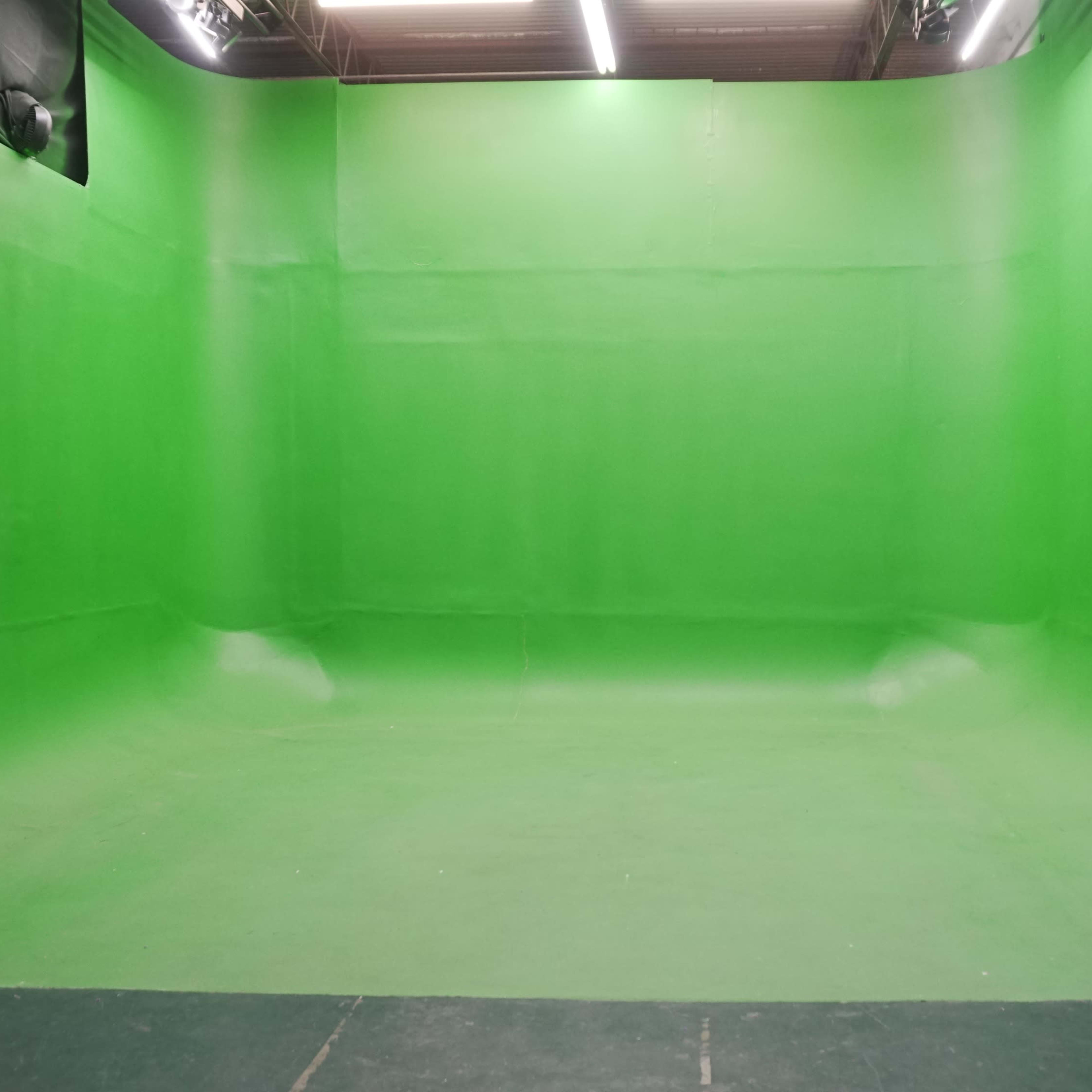 A large green screen studio with smooth green walls and floor.