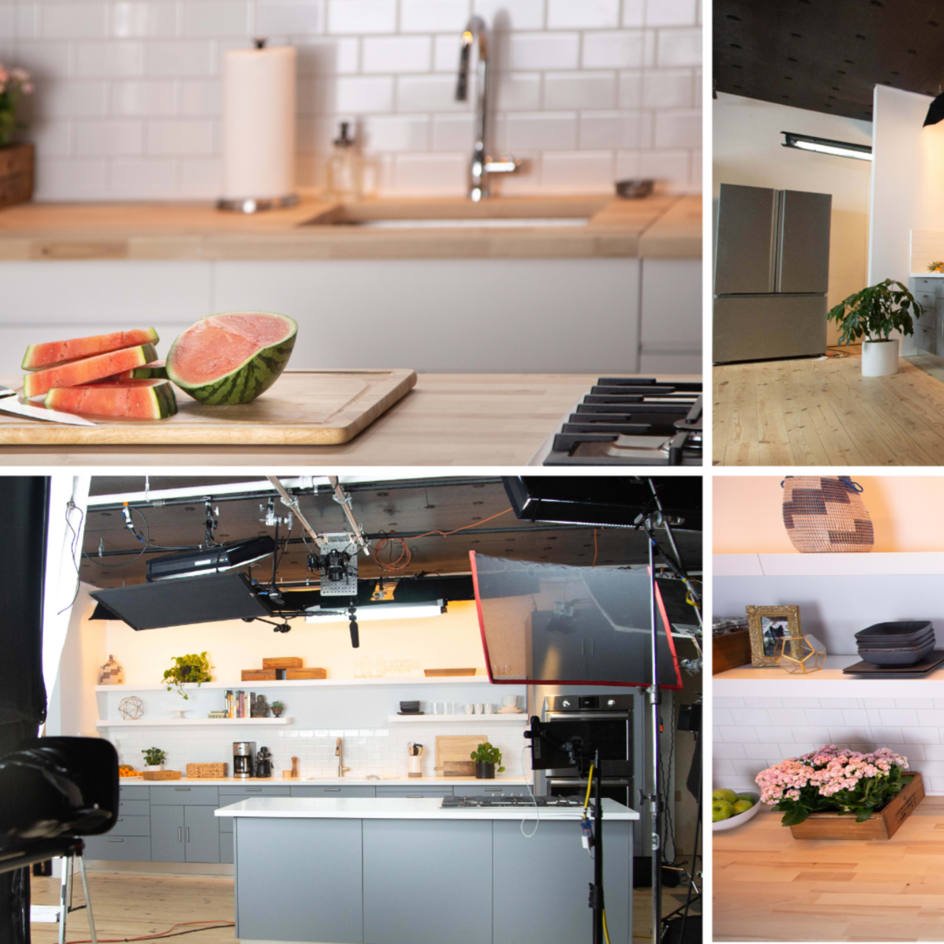 A modern kitchen setup with a light wood countertop, various kitchen appliances, fresh produce, and organized shelves displaying cookware and plants.