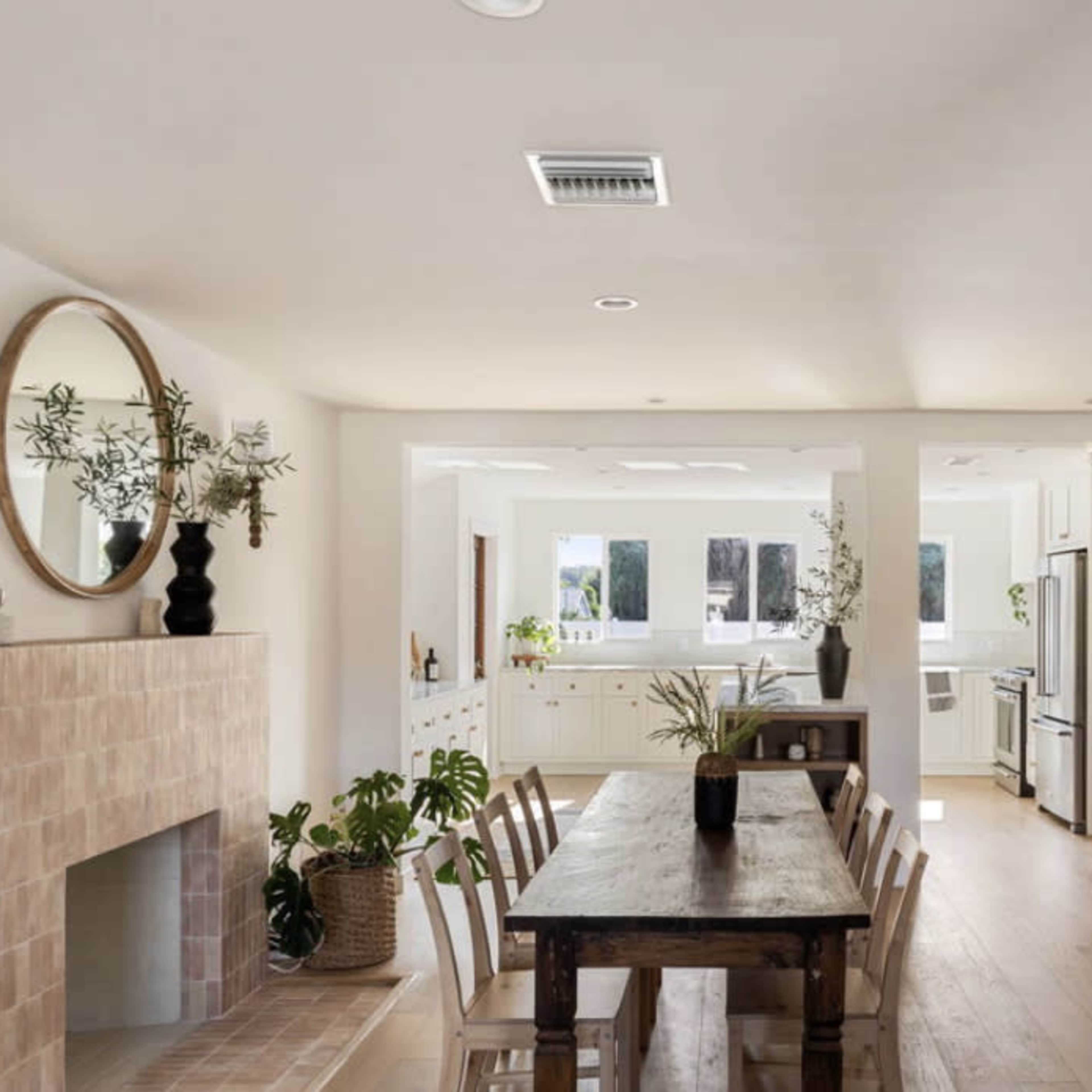 A modern kitchen and dining area with a wooden table, a fireplace, and large windows allowing natural light.