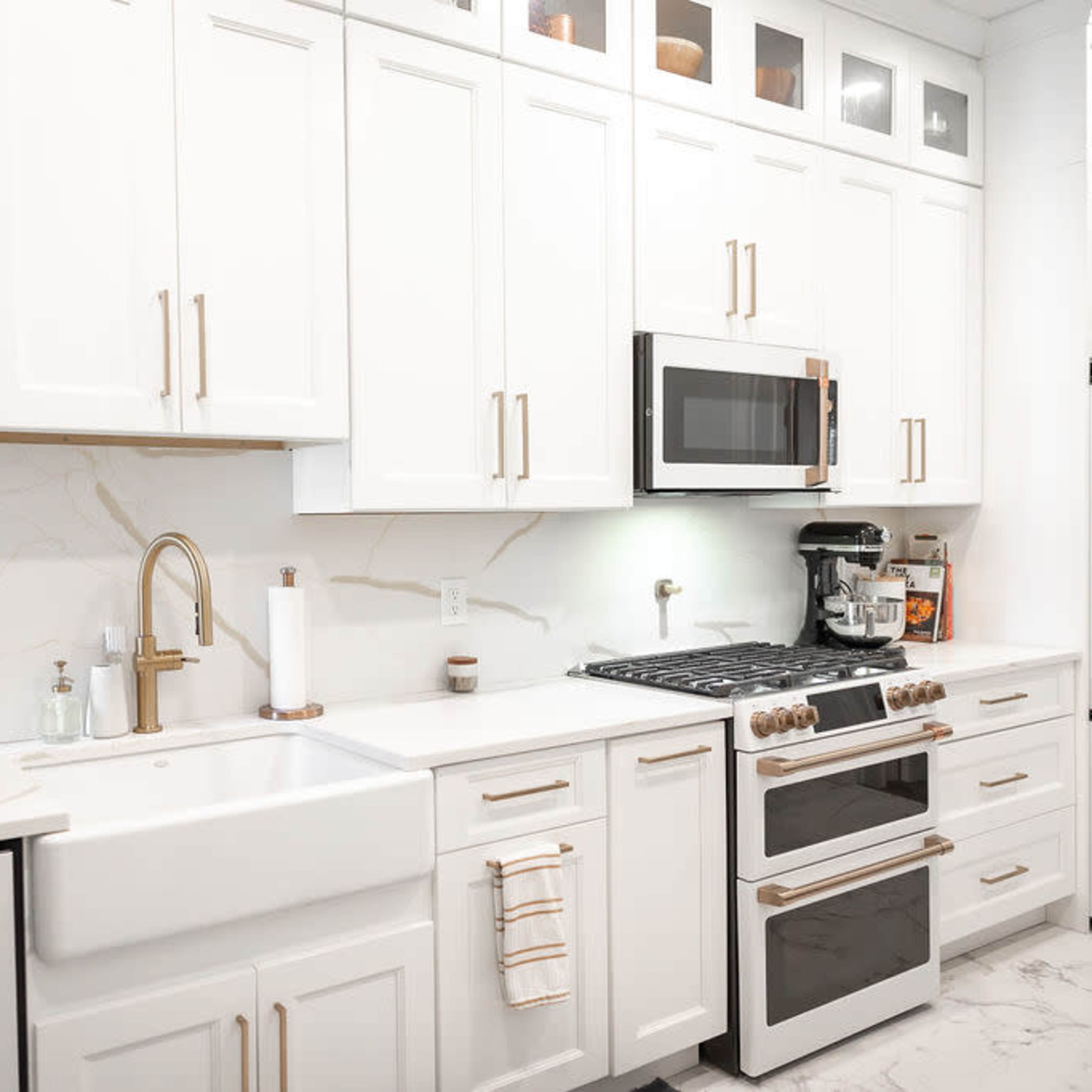 A modern kitchen featuring white cabinets, stainless steel appliances, and a large farmhouse sink.