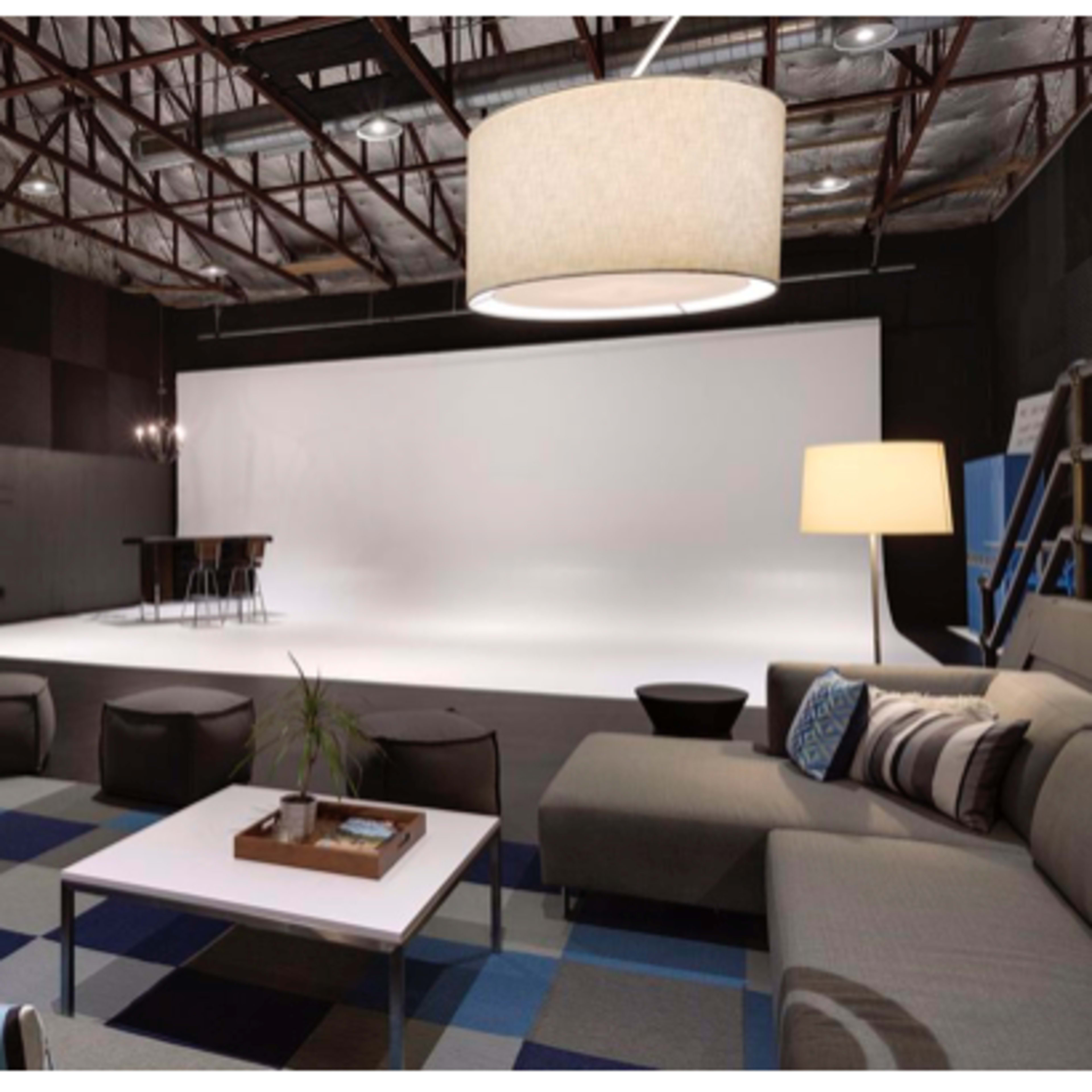 A spacious photography studio features a lounge area with couches, coffee tables, and aesthetic lighting, adjacent to a bright white backdrop.